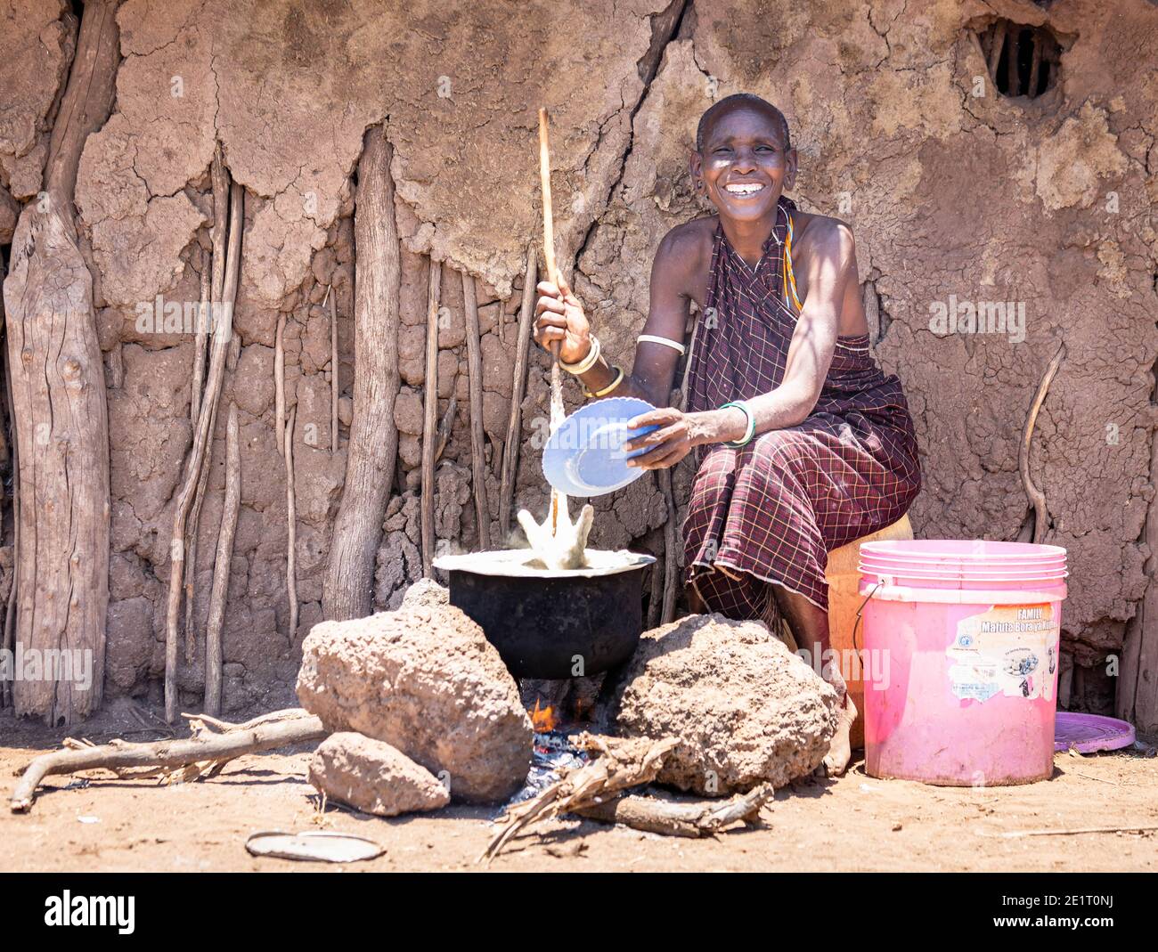 Belle femme de Datoga, au milieu, qui cuisine Ugali à l'extérieur de sa maison Banque D'Images