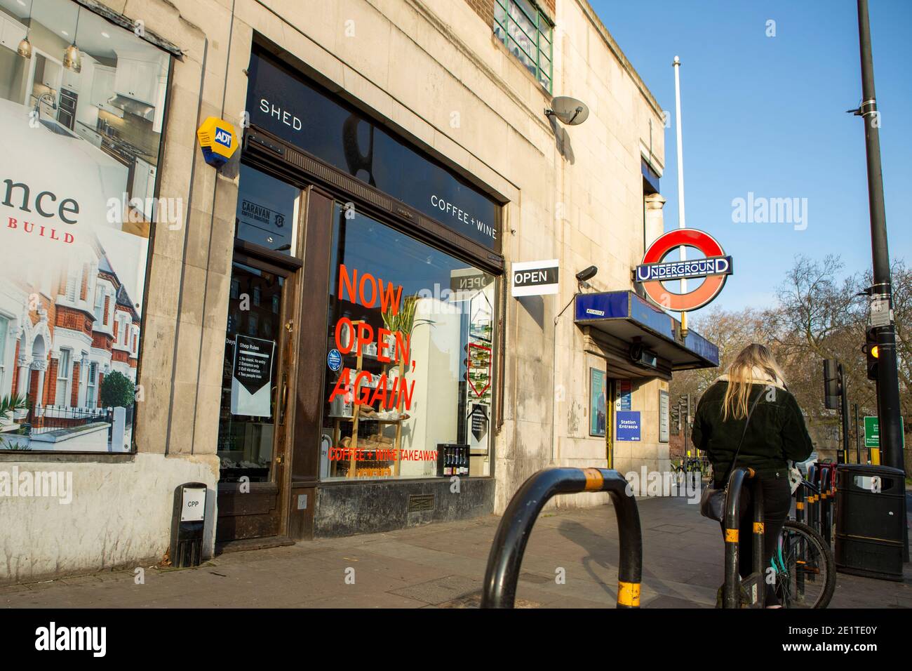 Lady se tient près d'un café à Clapham South avec un panneau de l'ouverture à nouveau. Banque D'Images