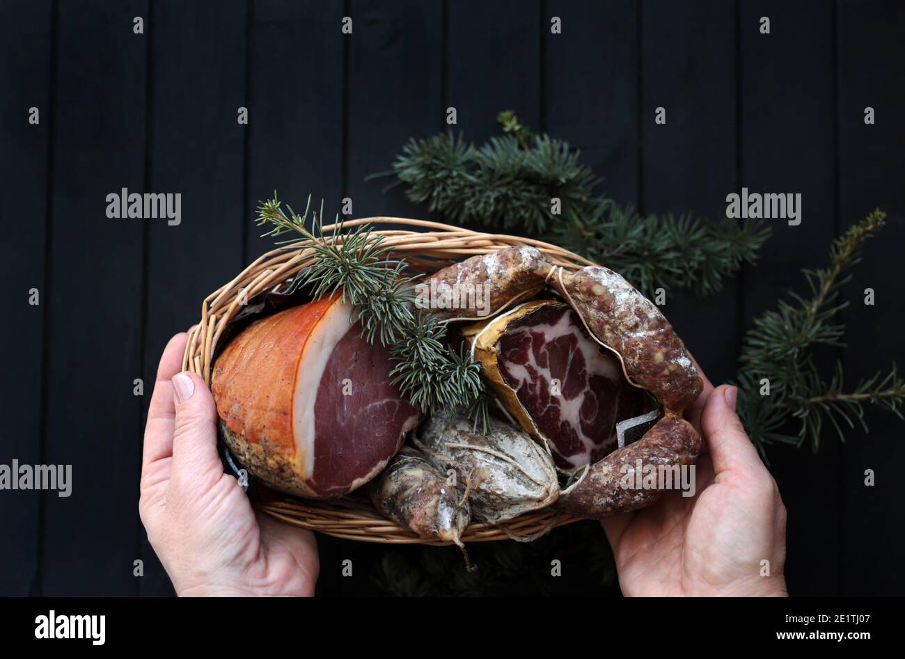 Panier avec salami, coppa et prosciutto sur fond de bois foncé. Spécialités italiennes. Décorations de Noël. Banque D'Images