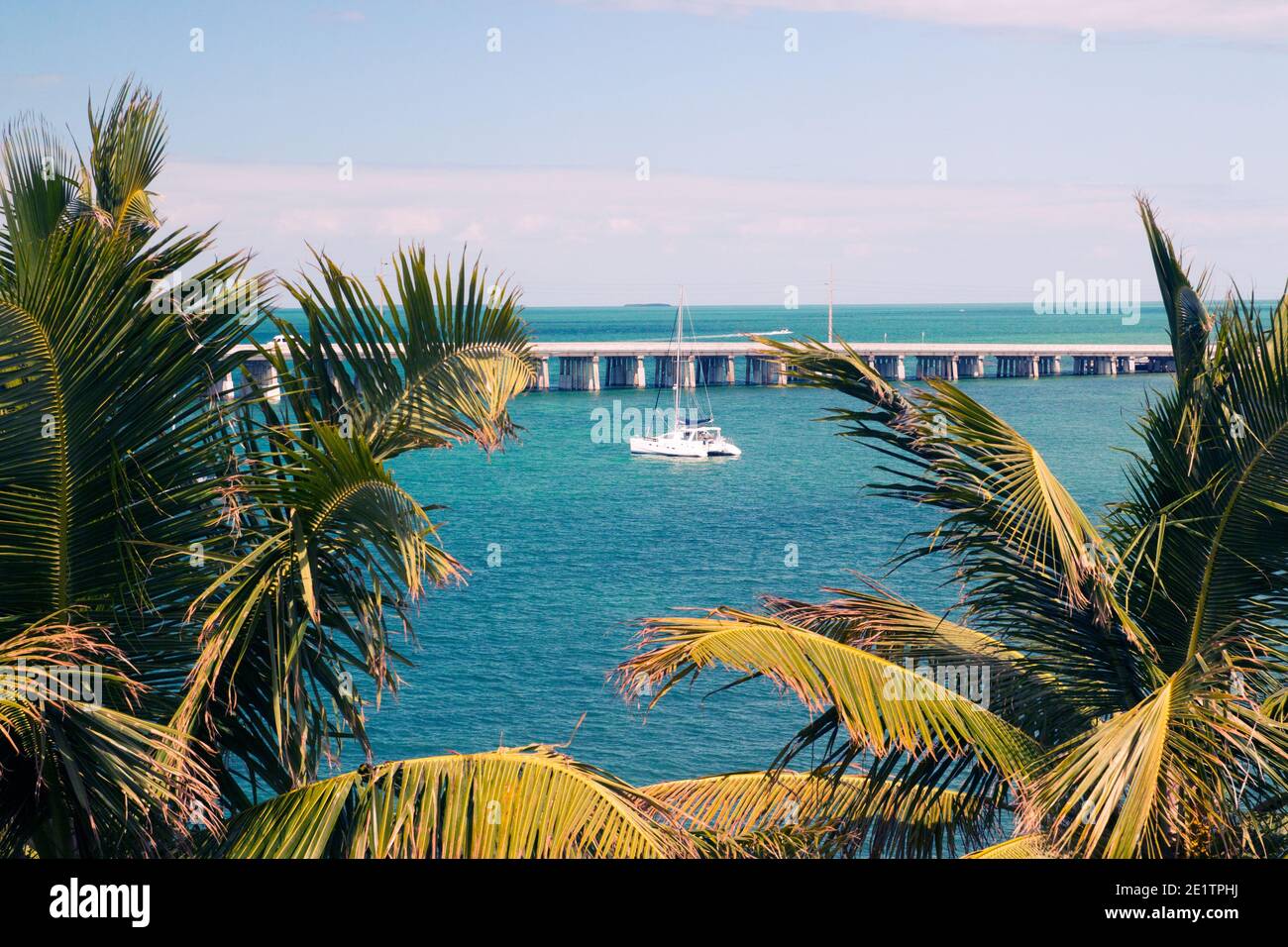 Vue à travers les palmiers tropicaux jusqu'au lagon bleu avec yacht de luxe amarré, pont de 12 miles sur fond, Bahia Honda Key Florida Banque D'Images