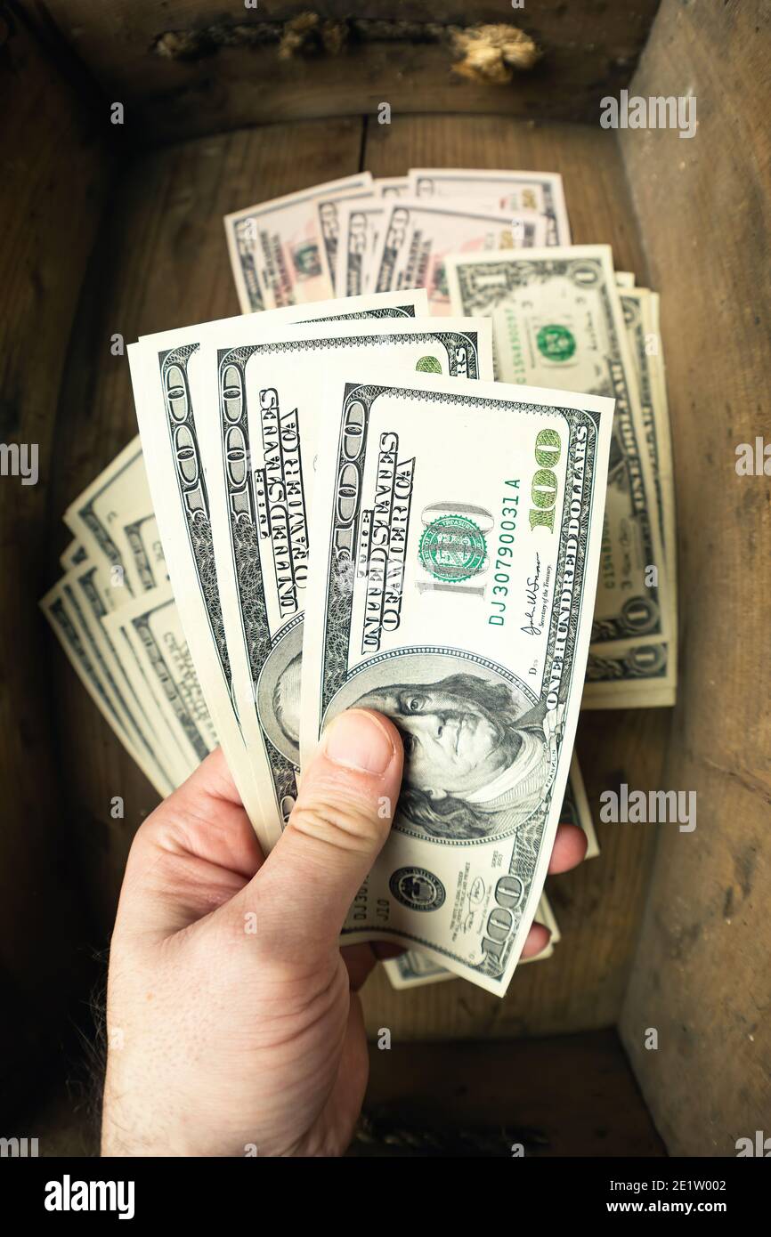 Main tenant cent billets américains avec le portrait du président Franklin sur fond de tiroir en bois. Espèces de billets de cent dollars, papier curren argent Banque D'Images