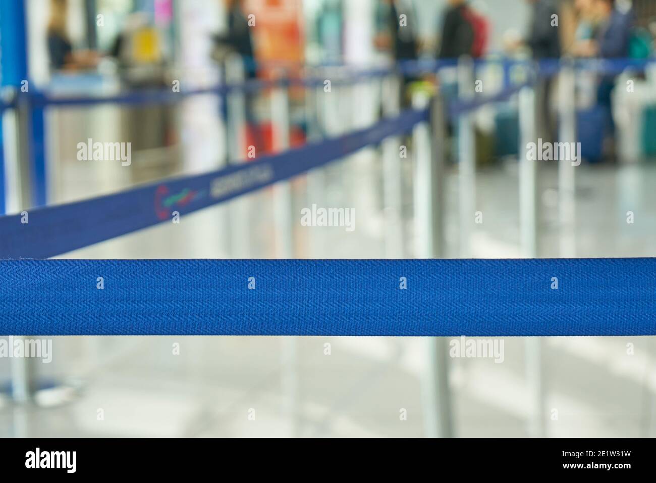 Fixation de la ceinture rétractable. Barrière à ruban portable. Bande de clôture de couleur bleue. Scène de l'aéroport avec passagers en attente d'embarquement Banque D'Images