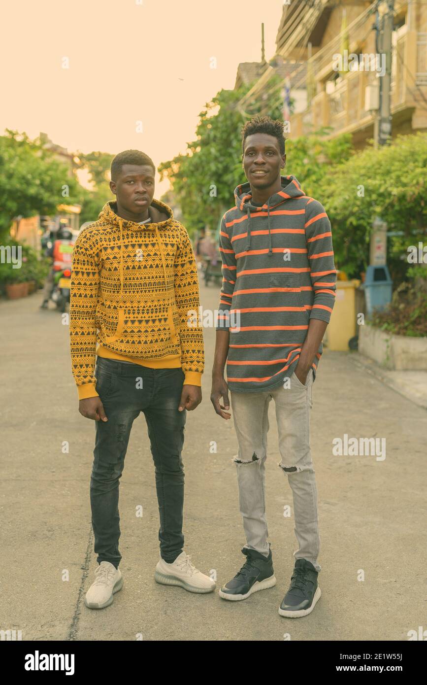Corps complet tourné de deux jeunes happy black African friends smiling while standing outdoors Banque D'Images