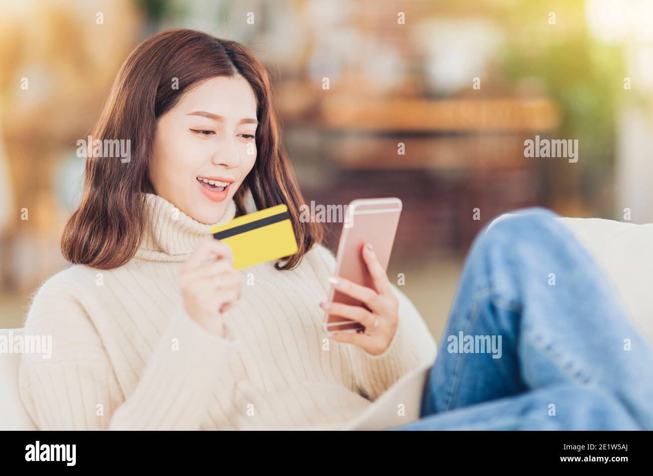 fille assise sur un canapé et shopping en ligne par smartphone Banque D'Images