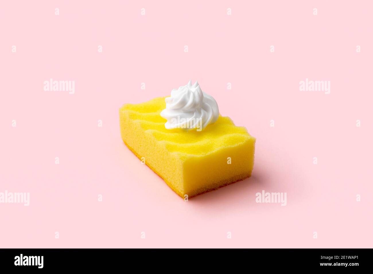 Éponge jaune pour laver la vaisselle avec mousse sur fond rose Banque D'Images