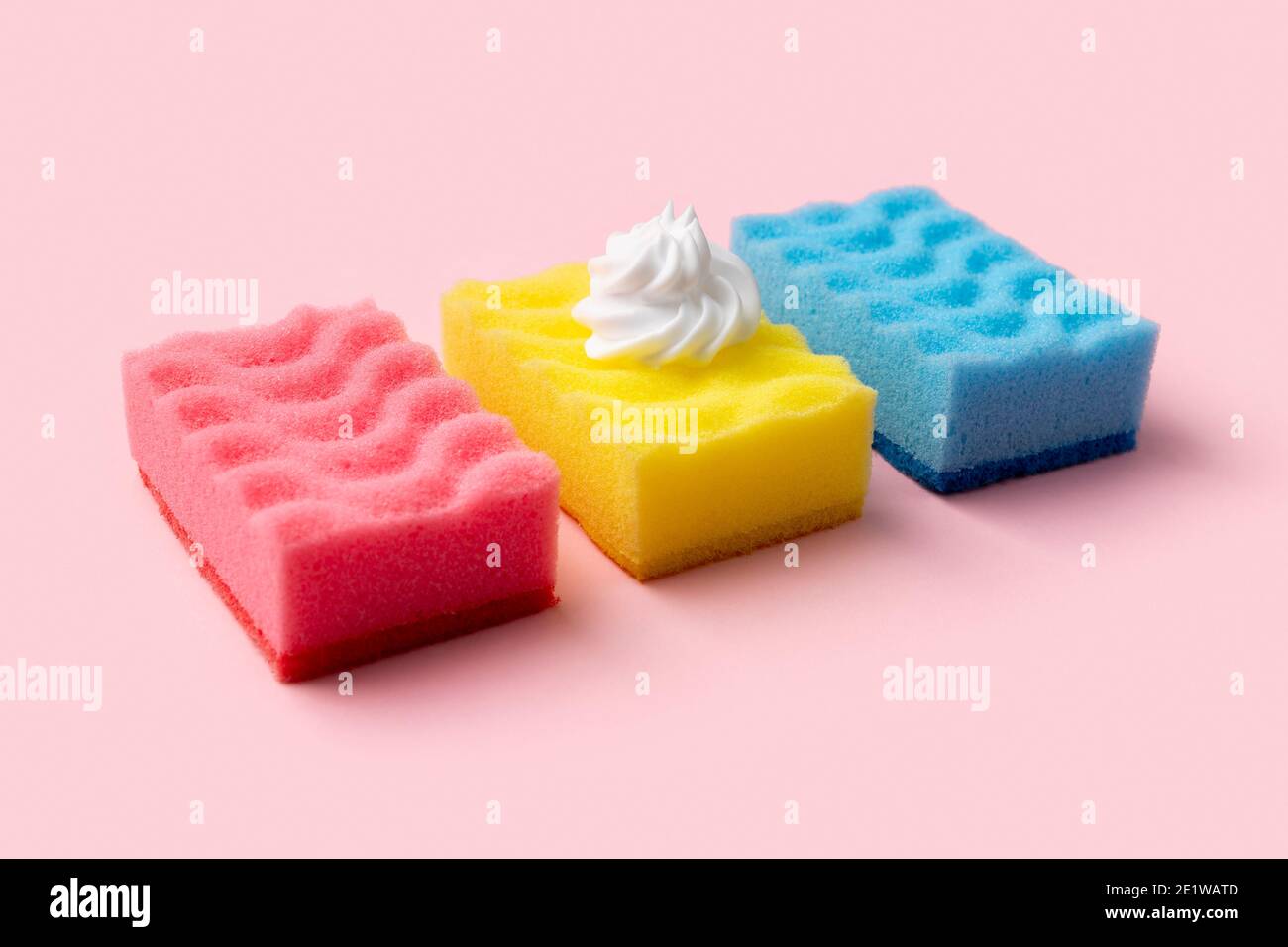 Éponges colorées pour laver la vaisselle avec mousse sur fond rose Banque D'Images