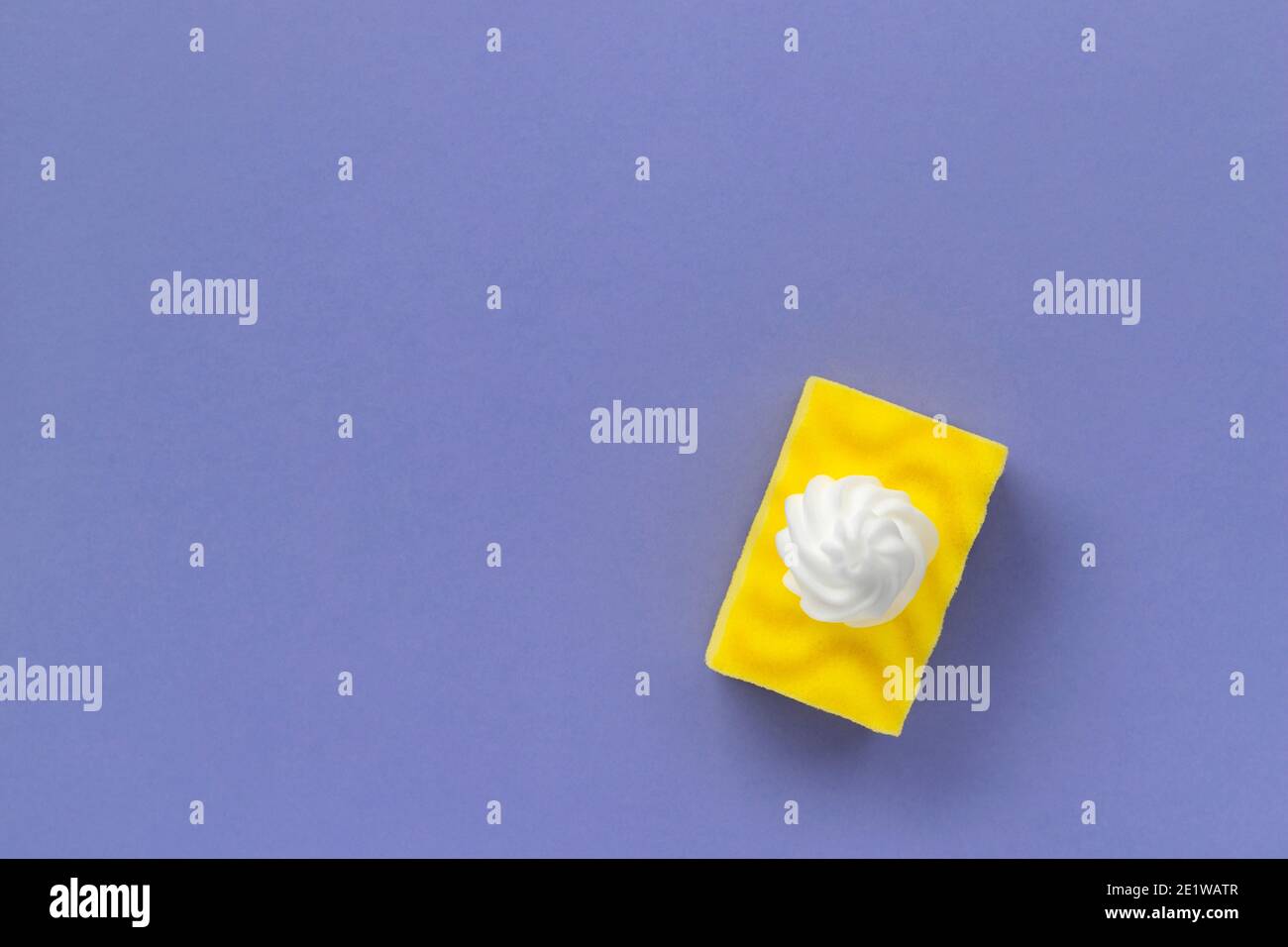 Éponge jaune pour laver la vaisselle avec mousse sur fond violet Banque D'Images