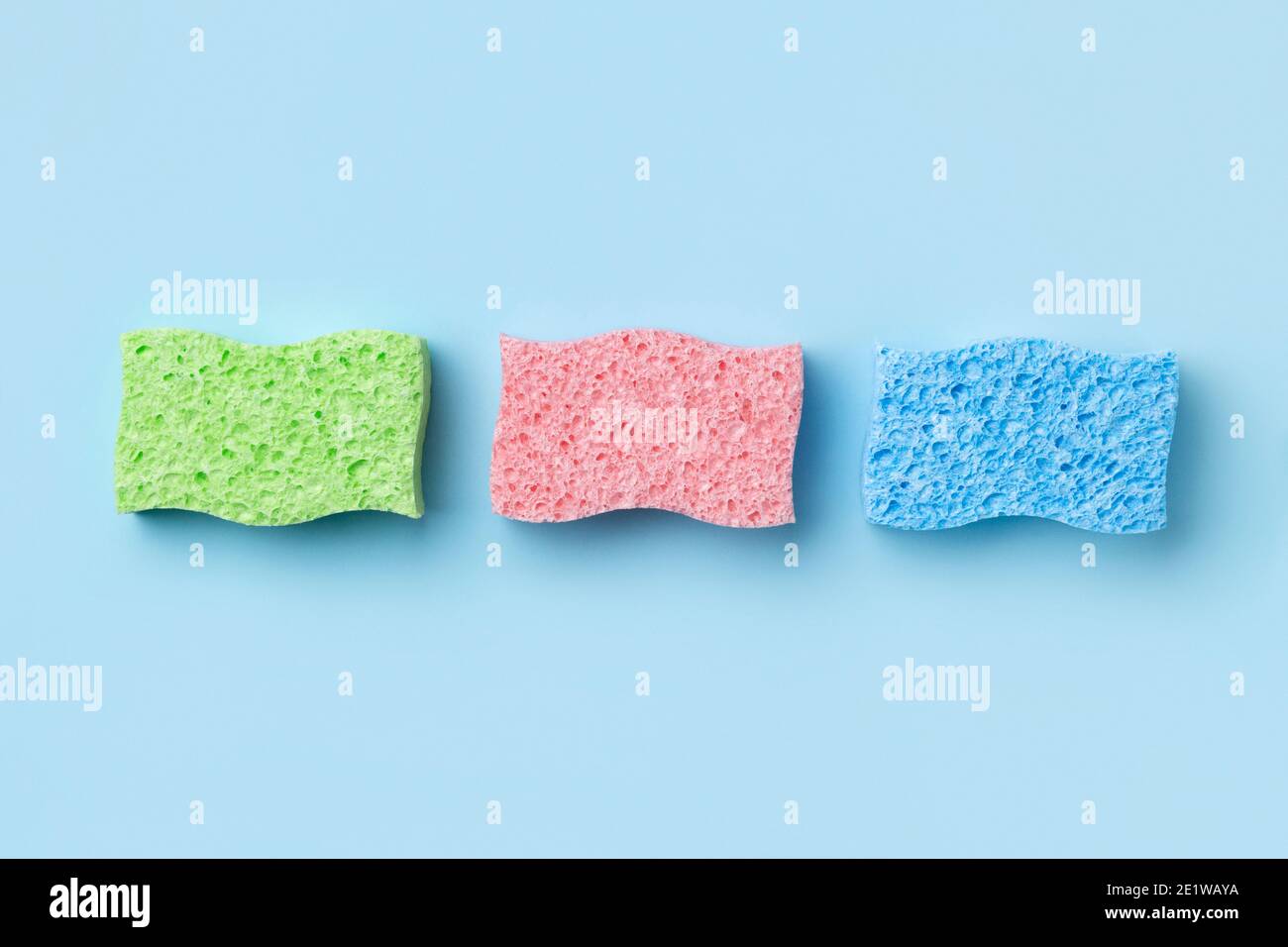 Disposition créative avec éponges pour le lavage de la vaisselle sur fond bleu. Banque D'Images