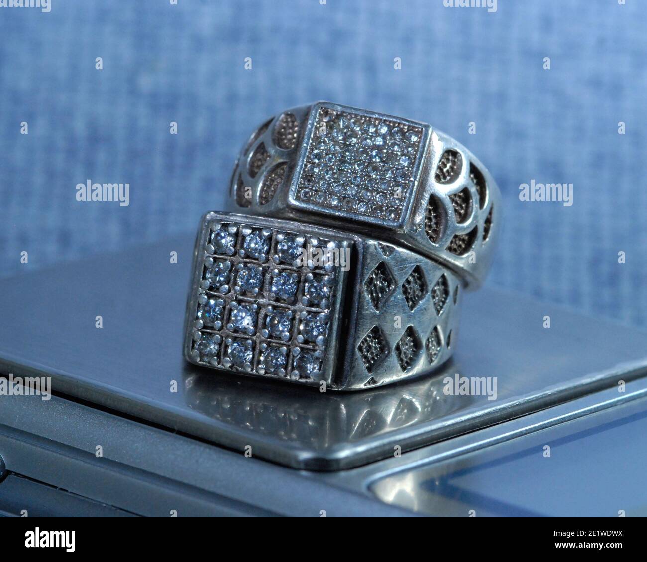Gros plan d'une paire d'anneaux d'argent cloués de pierres de zirconium pour hommes et femmes, sur une balance électronique. Banque D'Images