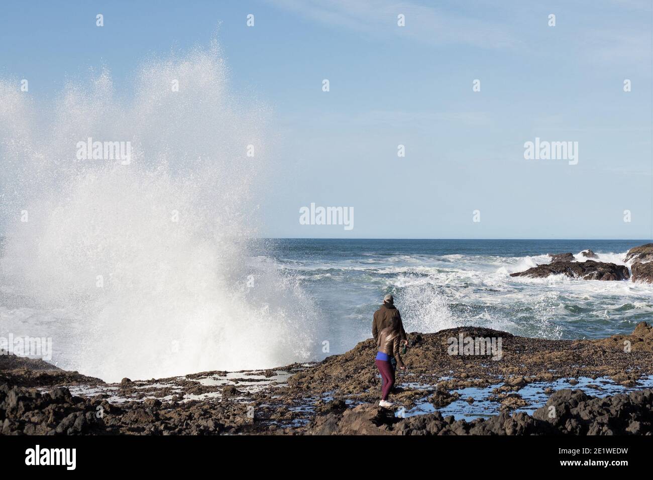 Un couple regardant une énorme vague s'écraser sur les rochers près de Yachats, Oregon. Banque D'Images