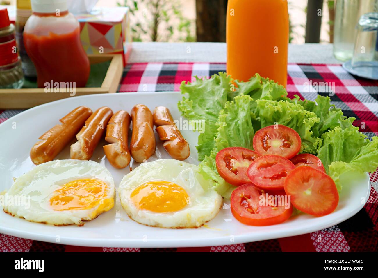 Assiette d'œufs frits et de saucisses avec salade fraîche pour petit déjeuner servi sur la table Banque D'Images