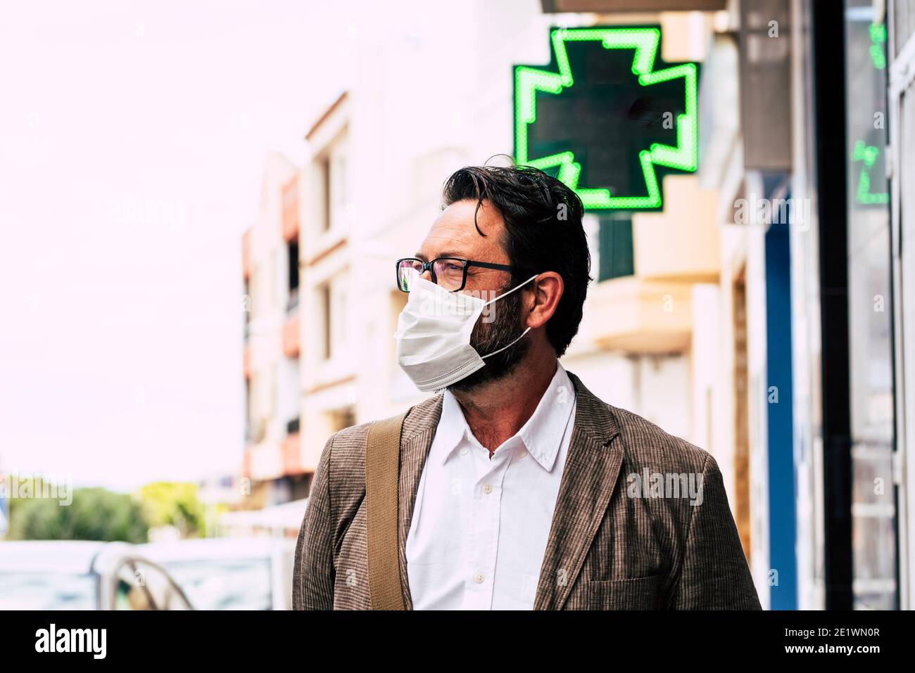 Homme adulte marchant dans la rue portant un masque médical à l'extérieur pour le coronavirus covid-19 restrictions saines - personnes avec protection jetable système Banque D'Images