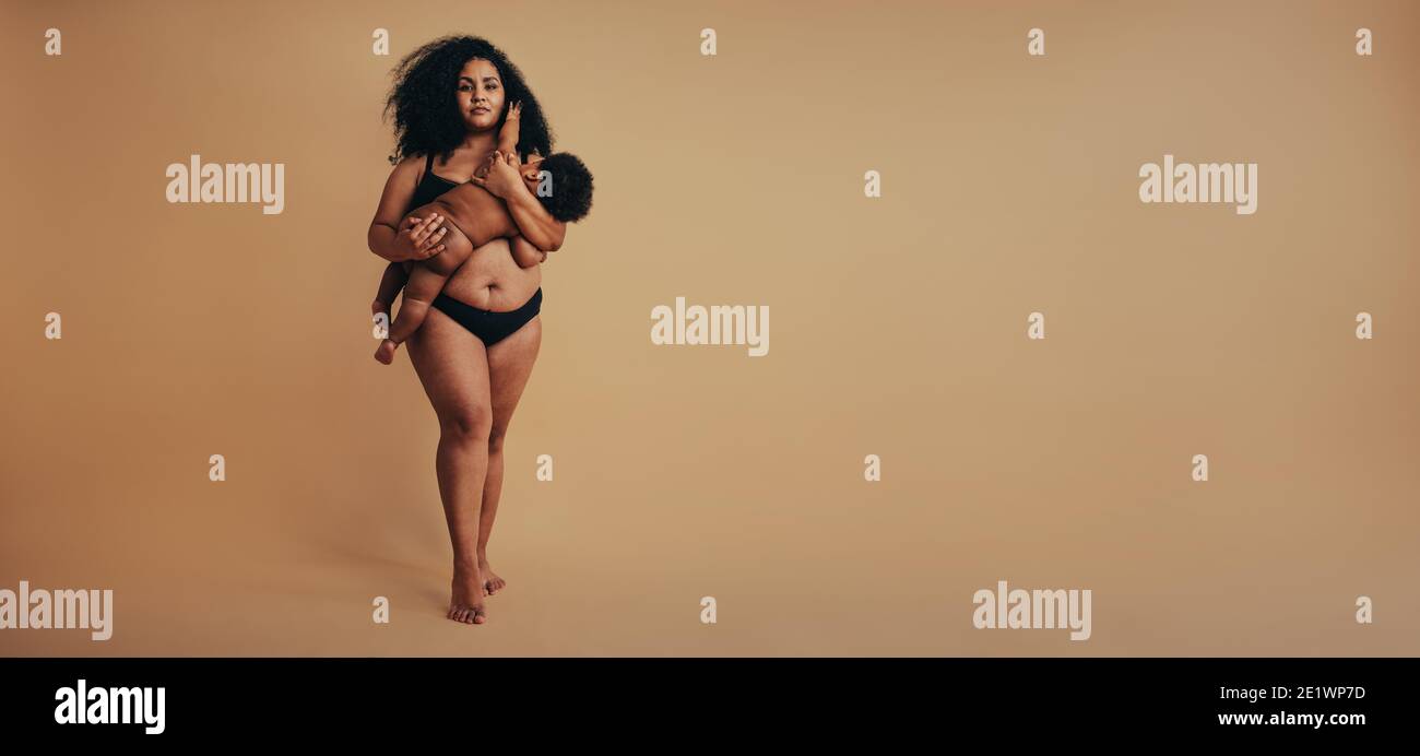 Pleine Longueur De Femme Debout Sur Fond Marron Allaitant Son Nouveau Ne Femme Africaine Qui Allaite Son Bebe Photo Stock Alamy