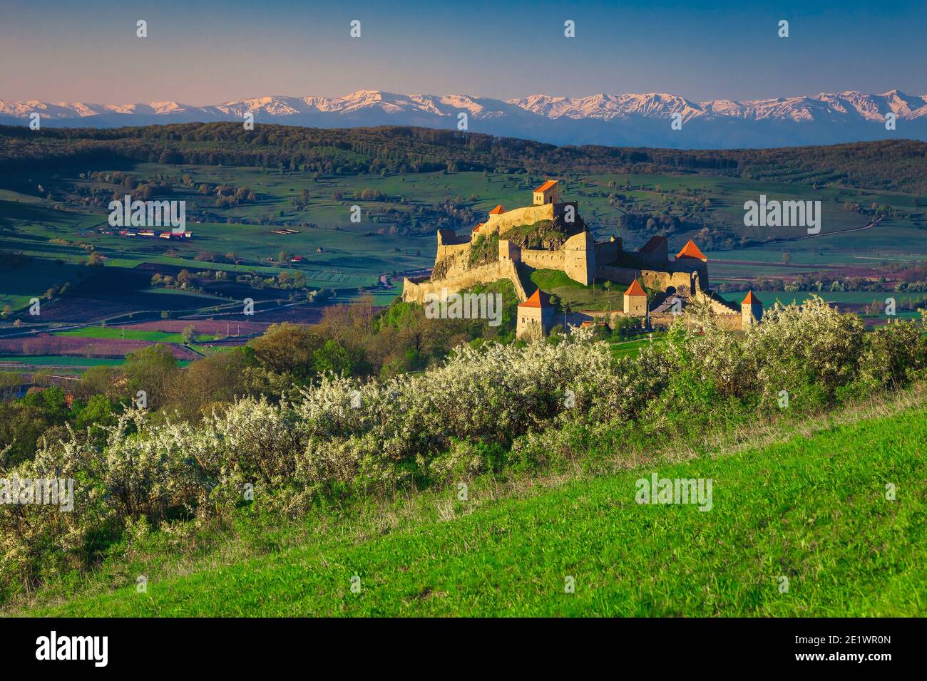Célèbre attraction touristique et destination de voyage. Belle forteresse Rupea et des montagnes enneigées en arrière-plan au lever du soleil, Brasov, Transylvanie, Roumanie Banque D'Images
