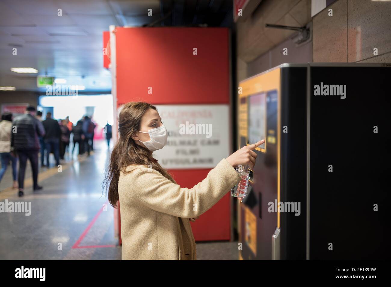 Belle fille portant masque médical de protection et vêtements à la mode utilise distributeur automatique pour l'argent.Nouveau concept normal pendant la pandémie corona, covid19. Banque D'Images