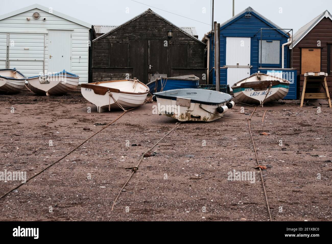 Cabanes de plage et petits bateaux en bois sur le sable à Teignmouth au début de la journée d'automne, Devon, Angleterre, Royaume-Uni Banque D'Images