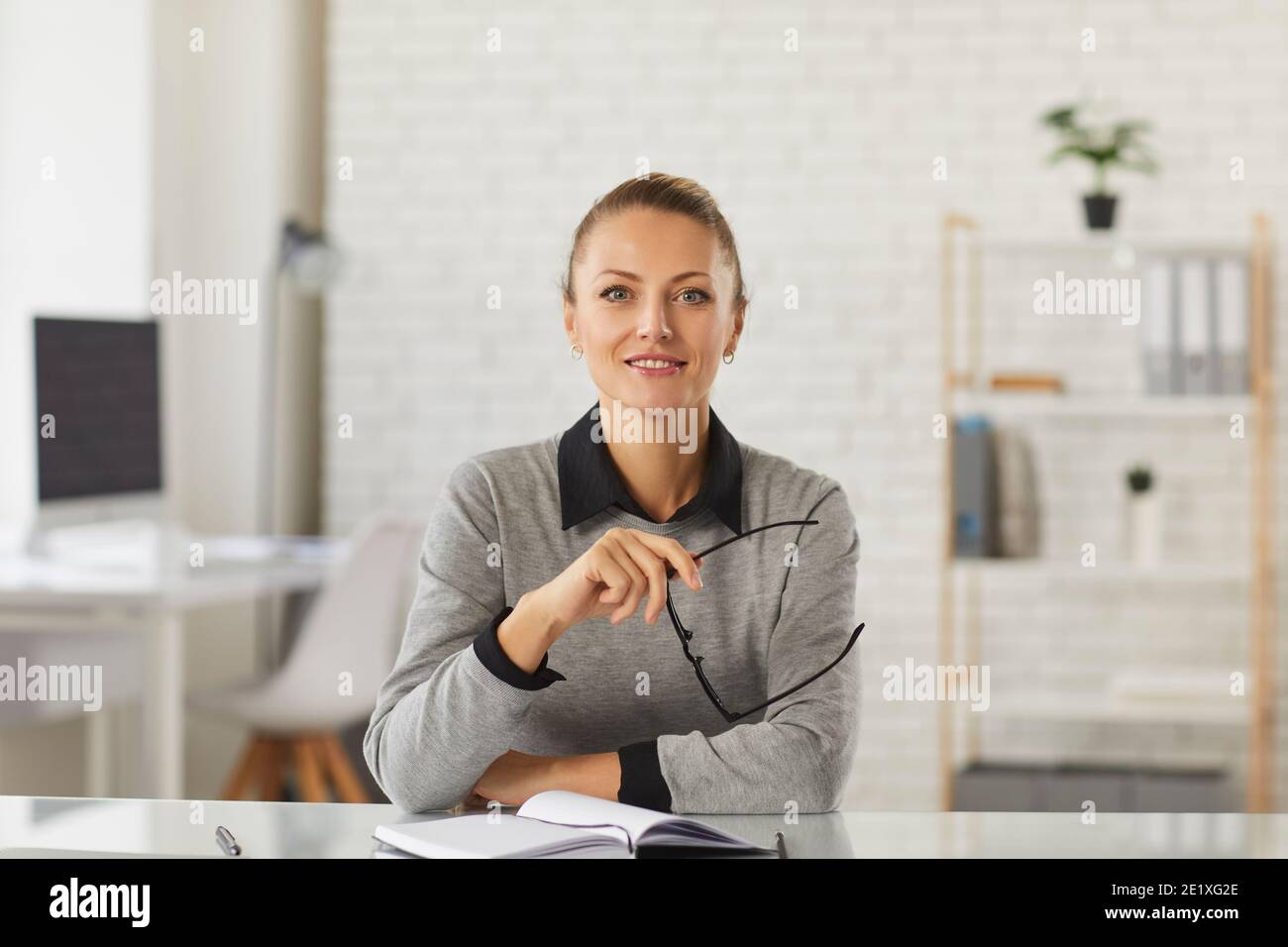 Jeune femme souriante employée de bureau assise et regardant la caméra lors d'un appel vidéo professionnel Banque D'Images