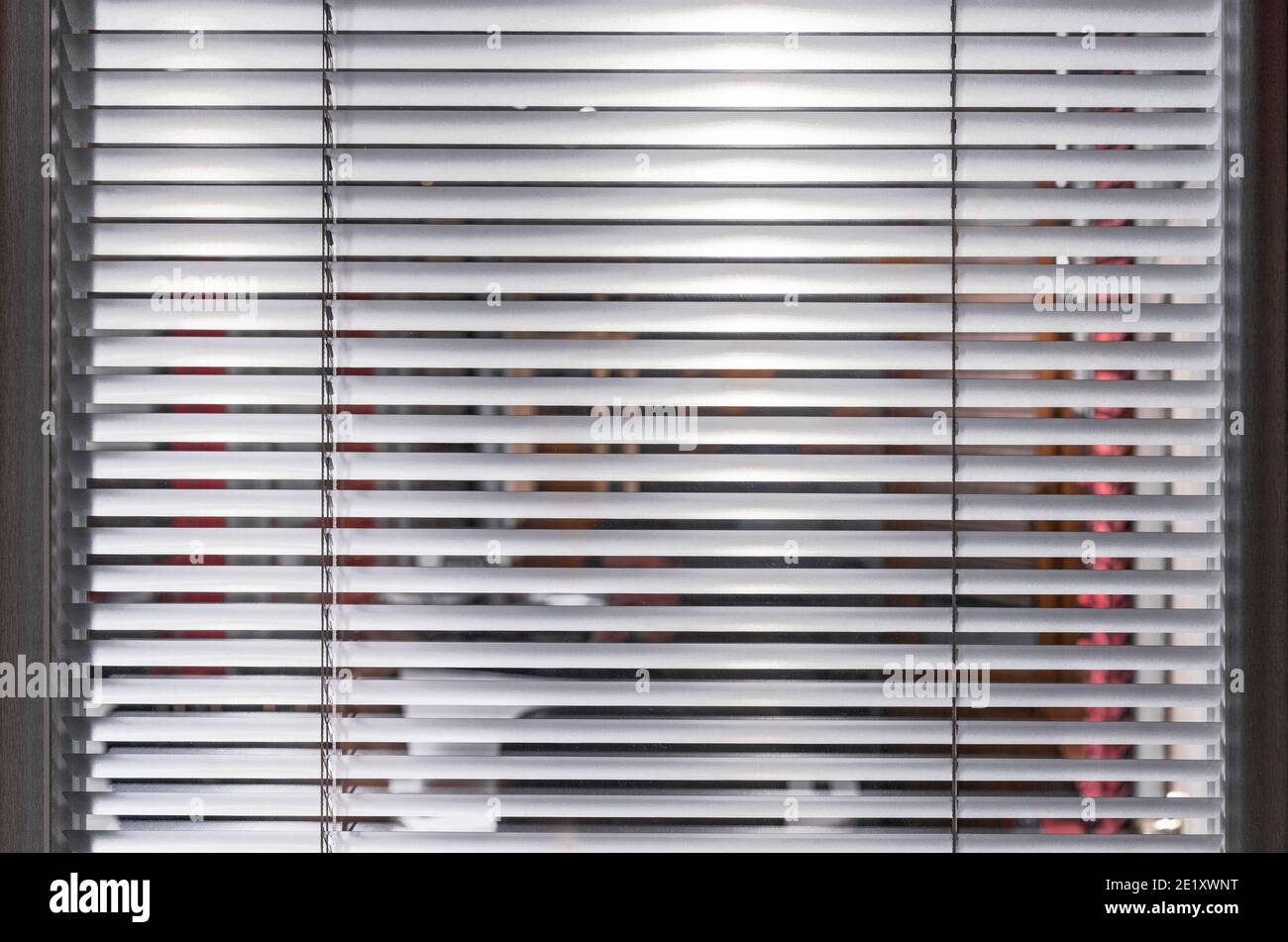Stores blancs légèrement fermés dans la fenêtre d'examen. Arrière-plan avec stores horizontaux. Banque D'Images