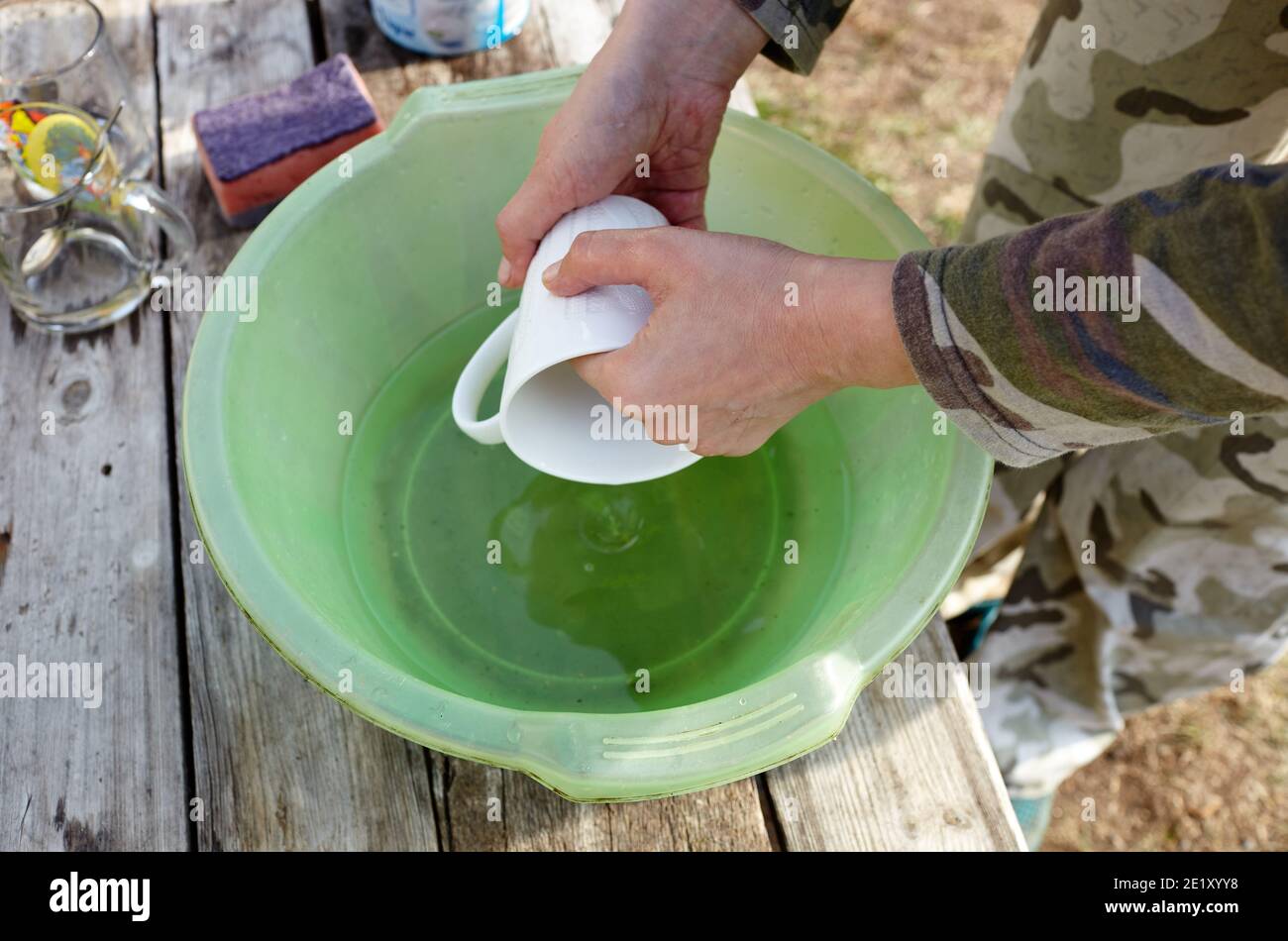 Lavage de vaisselle. Femme lavant une tasse en céramique dans la cour de banlieue, en gros plan Banque D'Images