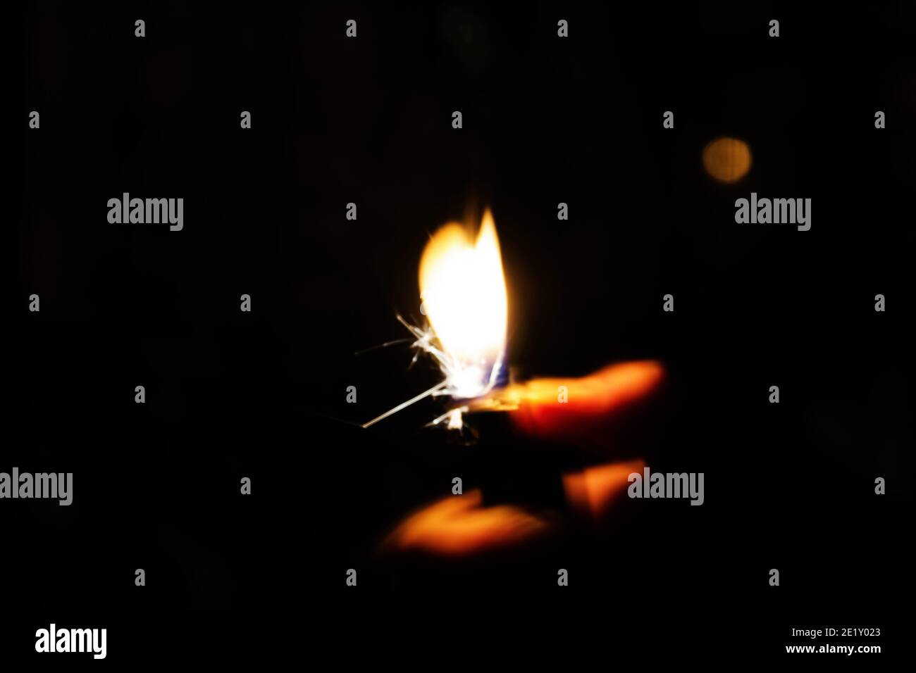 Une femme allume un briquet dans une pièce sombre. Photo conceptuelle et créative avec effet longue exposition. Banque D'Images