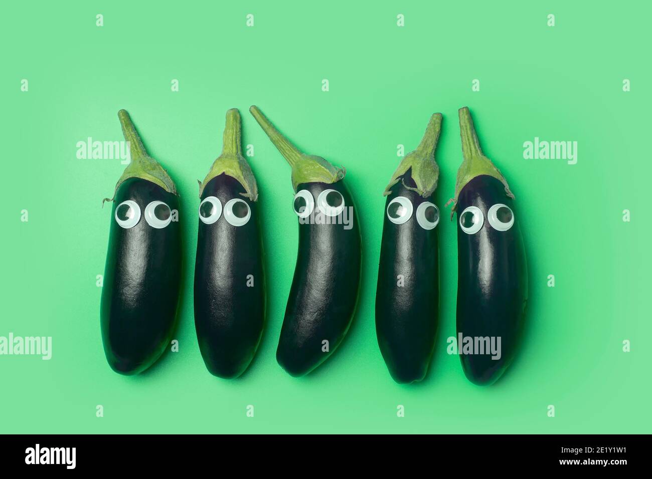 Concept de nourriture pour enfants. Aubergine avec les yeux sur fond vert coloré. Des légumes et des aliments amusants pour les enfants Banque D'Images