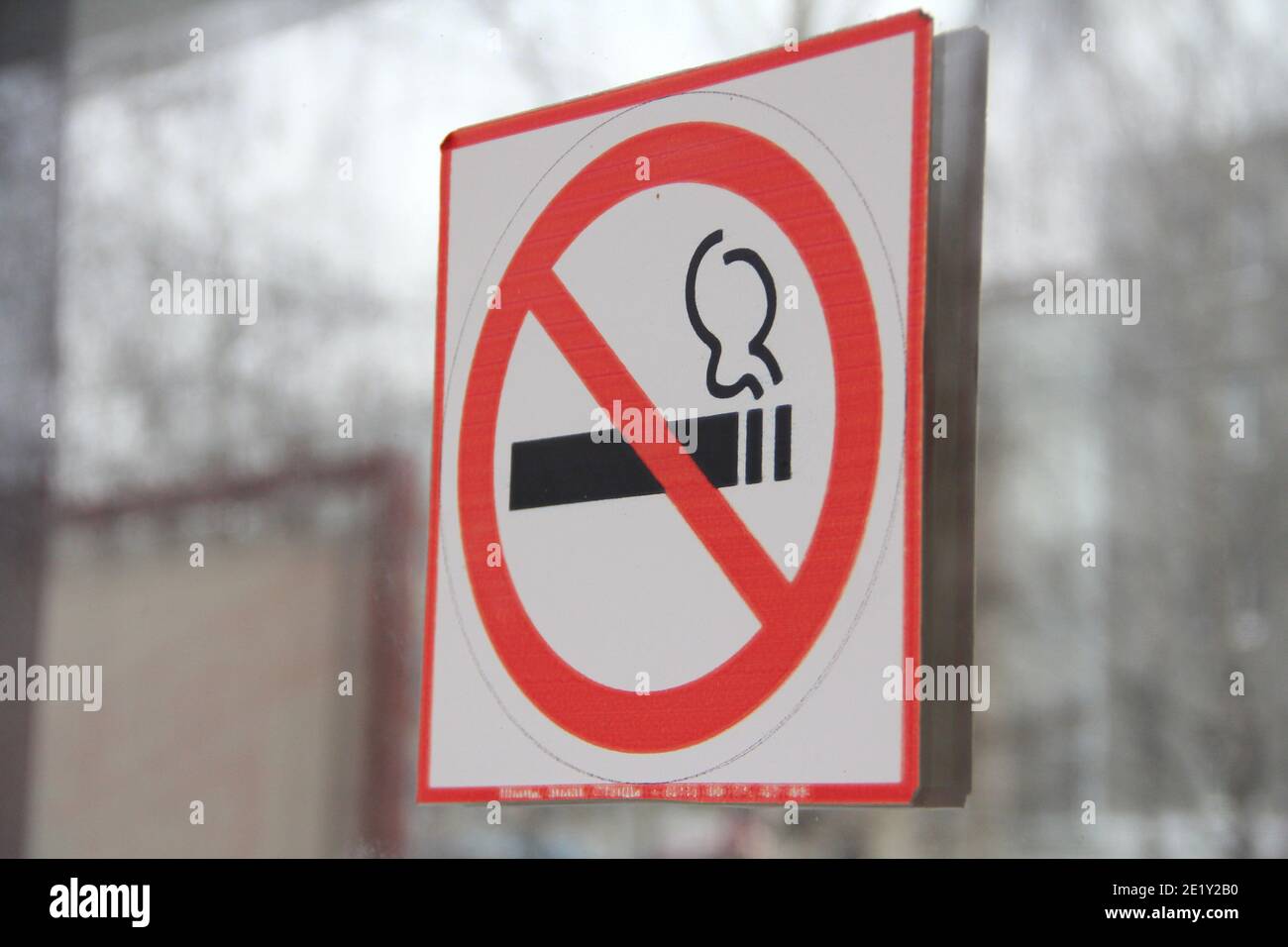 Panneau de non-fumeurs sur porte en verre, concept de soins de santé, renoncement au tabac. Fumer de la cigarette dans un cercle rouge barré. Photo de stock avec espace vide Banque D'Images