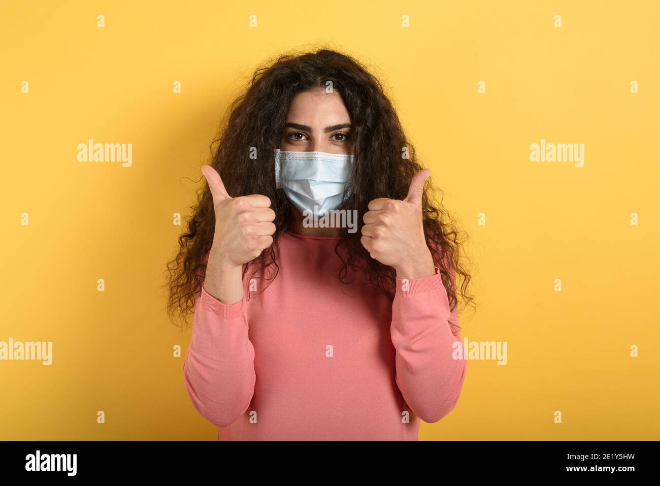 Fille est optimiste au sujet de la défaite du coronavirus covid 19. Fond jaune. Banque D'Images