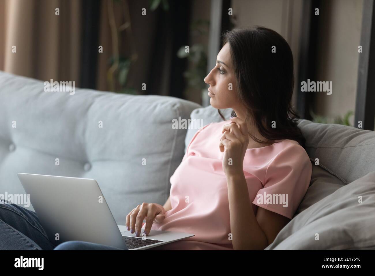 Une femme pensive travaille sur un ordinateur portable à la maison Banque D'Images