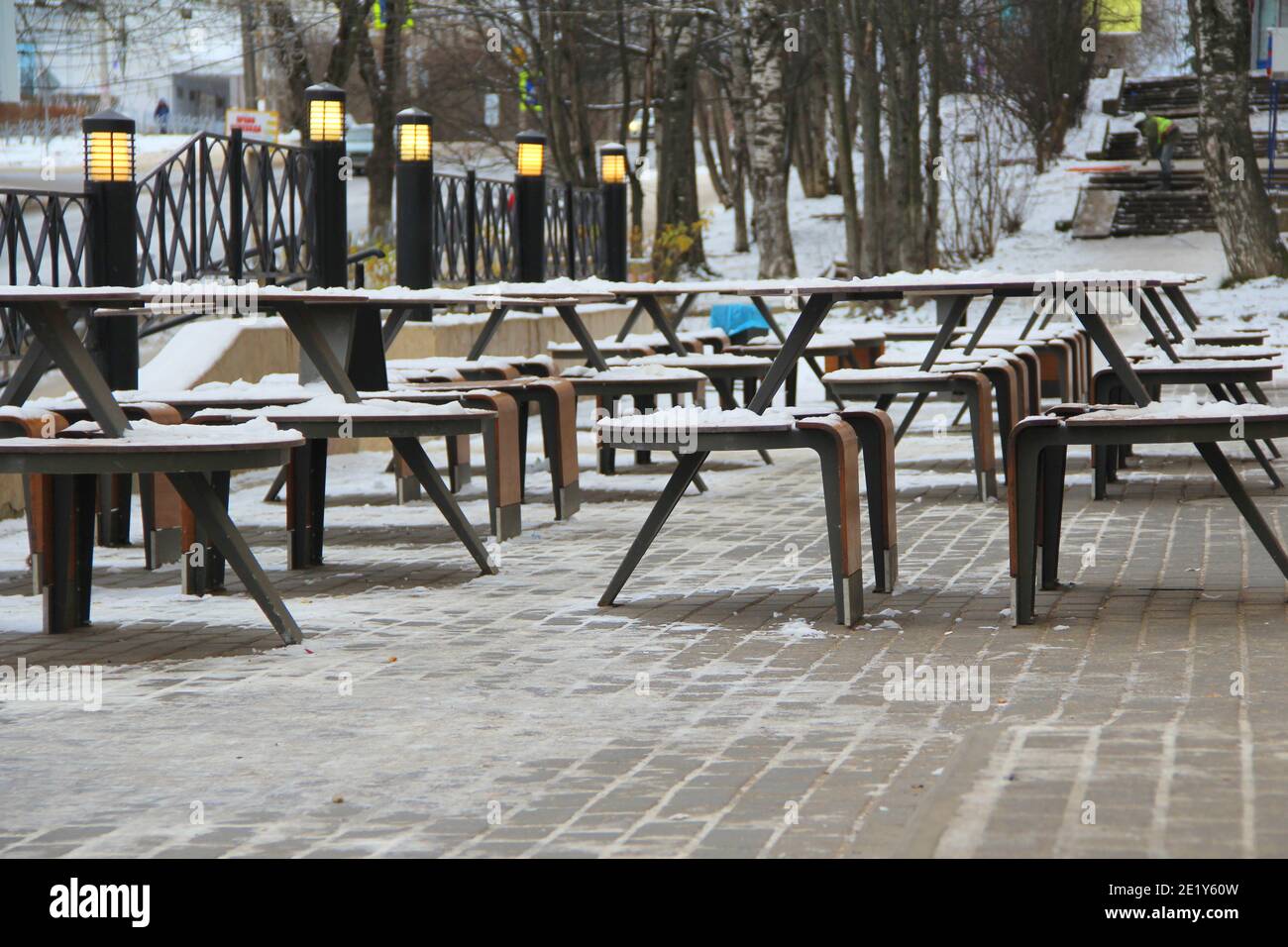 Des tables et des bancs couverts de neige se dressent sur la rue de la ville, sur un trottoir à côté du restaurant Winter en Russie. Banque D'Images