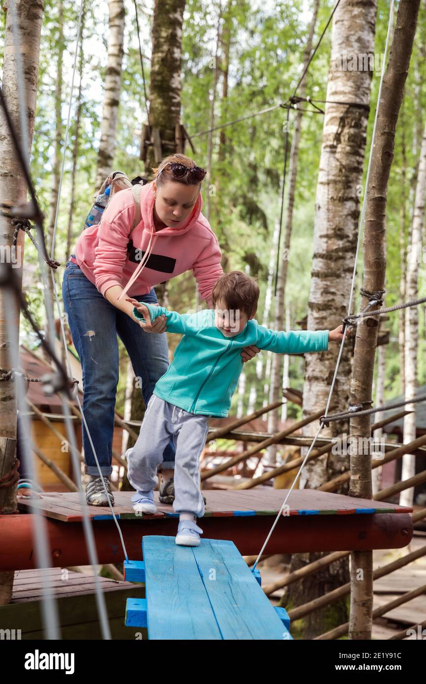 Mère avec son fils sur le parcours obstacle. Le parent aide l'enfant dans les endroits difficiles Banque D'Images