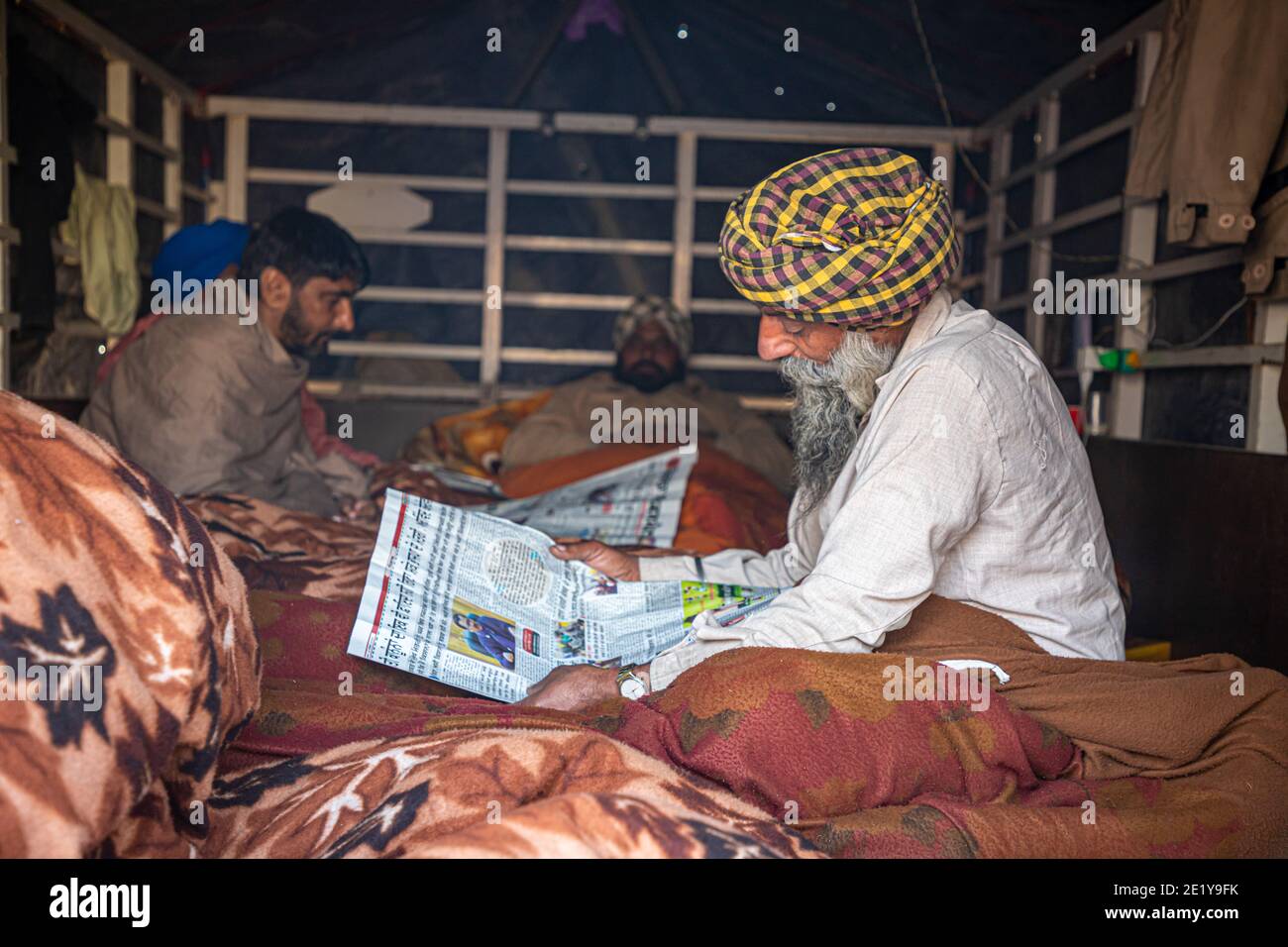 PORTRAIT D'UN MANIFESTANT D'AGRICULTEURS LISANT UN ARTICLE À LA FRONTIÈRE DE DELHI , ILS PROTESTENT CONTRE LA NOUVELLE LOI AGRICOLE ADOPTÉE PAR LE GOUVERNEMENT INDIEN. Banque D'Images