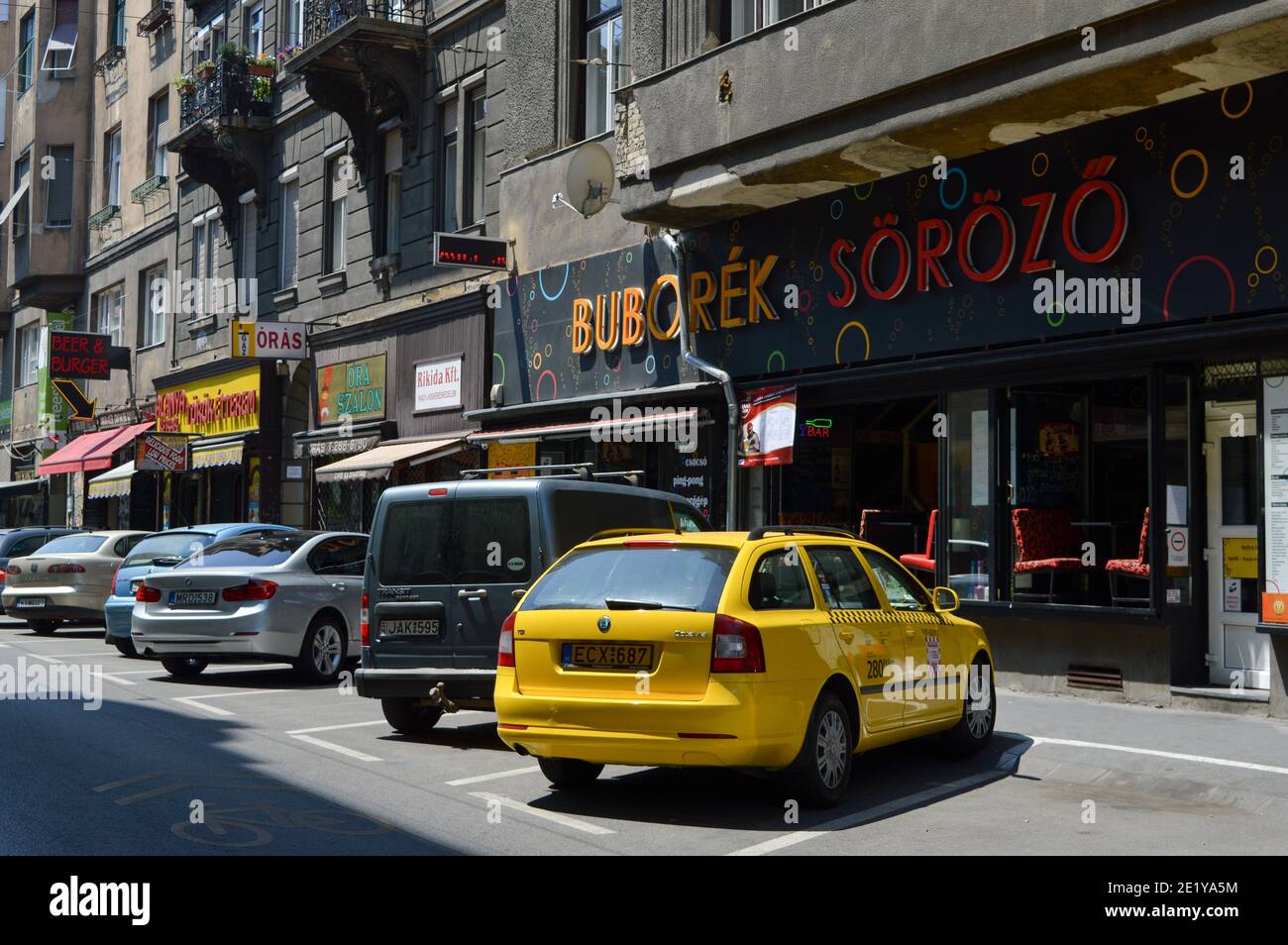 Budapest, Hongrie: Rue dans le centre-ville avec des voitures garées, taxi jaune et bar à bière Buborék Söröző Banque D'Images