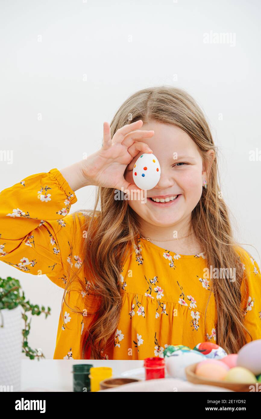 Une fillette souriante qui tient l'oeuf de pâques sur son œil Banque D'Images