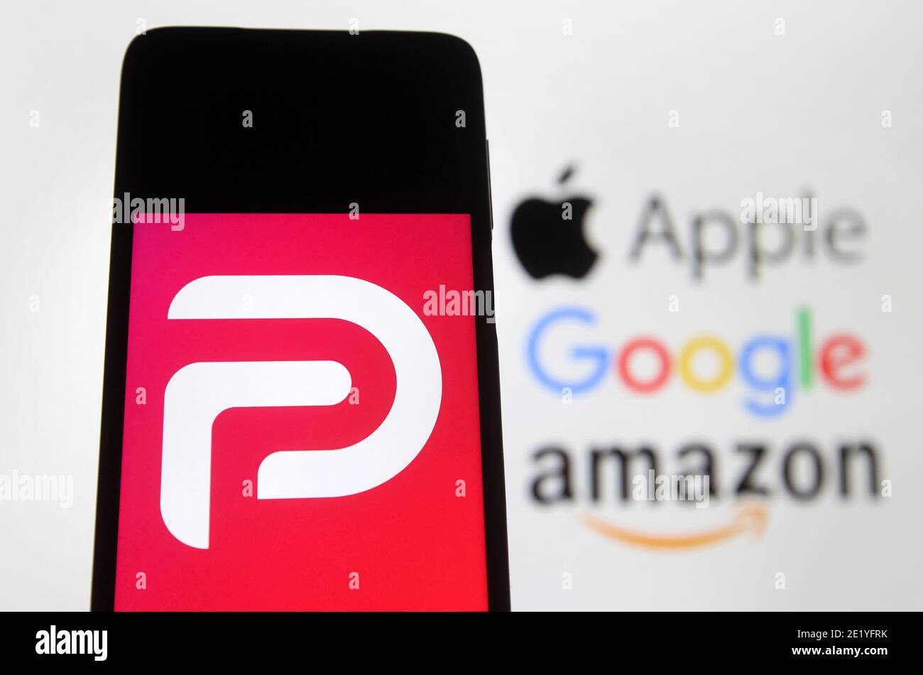 Dans cette illustration, le logo Parler affiché sur un smartphone avec les  logos Google, Amazon et Apple affichés sur l'écran du PC en  arrière-plan.Google, Apple et Amazon ont suspendu l'application de réseau