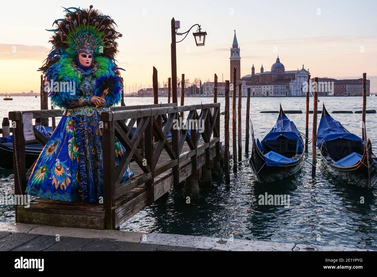 Femme habillée de costume traditionnel décoré et masque peint pendant le Carnaval de Venise avec le monastère de San Giorgio derrière, Venise, Italie Banque D'Images