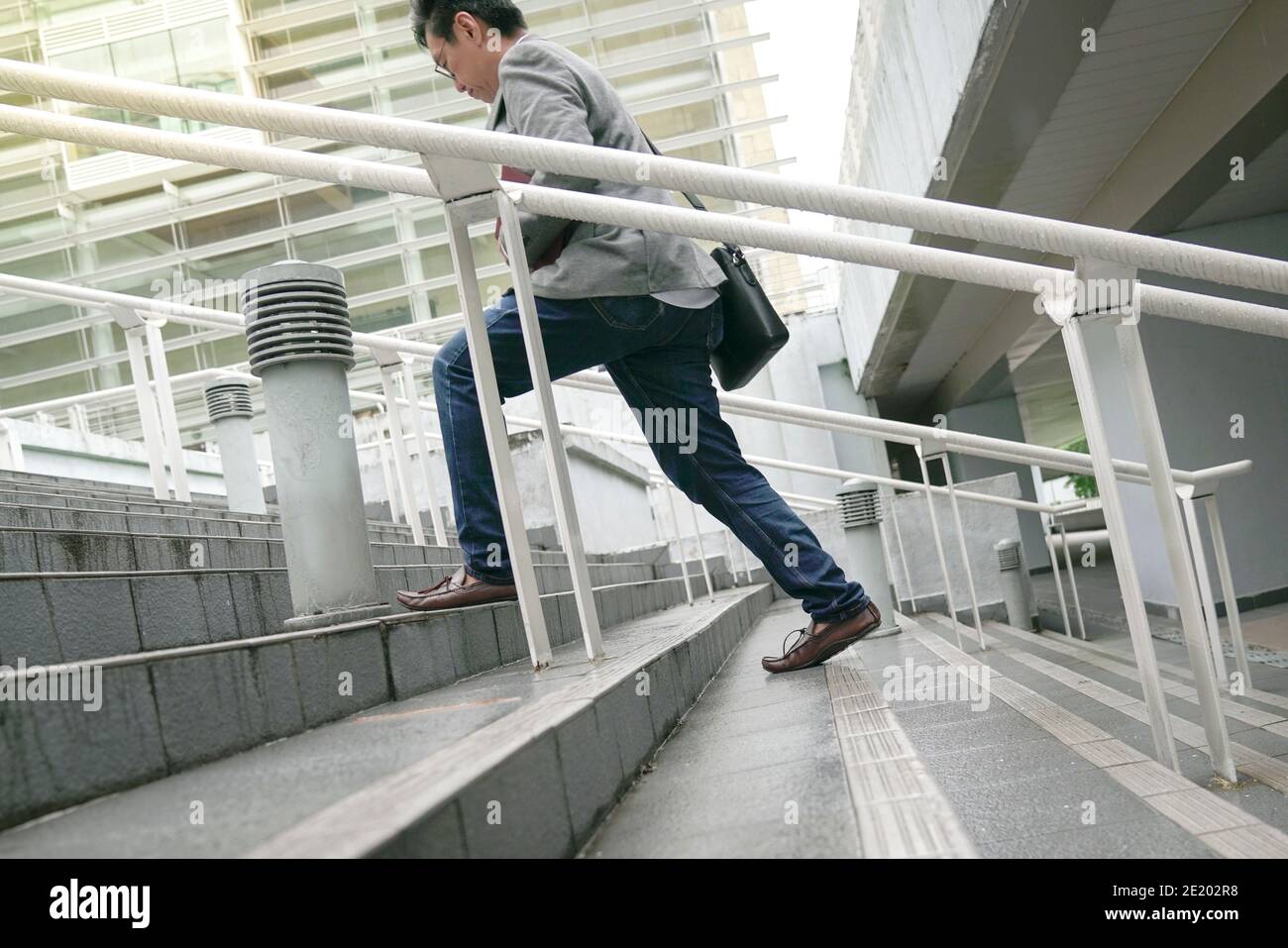 Homme d'affaires avec sac de travail monter les escaliers rapidement, se concentrer sur les jambes et les pieds. Concept d'échelle d'entreprise ou de réussite professionnelle. Banque D'Images