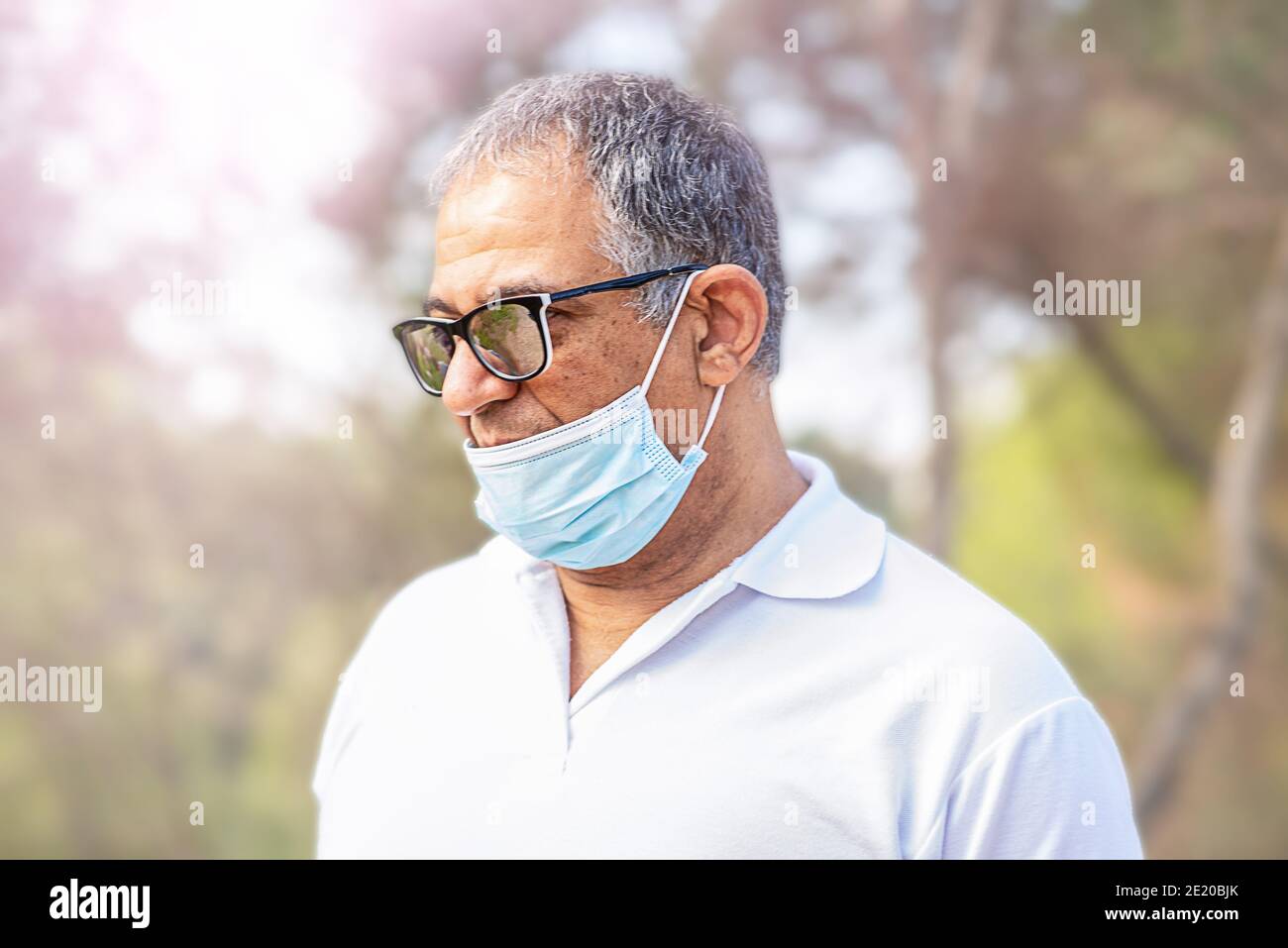 Portrait homme âgé seul voyageur porte un masque et voyage dans une forêt. Le vieil homme porte un masque facial, de la mauvaise façon, l'usure incorrecte - les masques devraient couvrir le nez. Banque D'Images