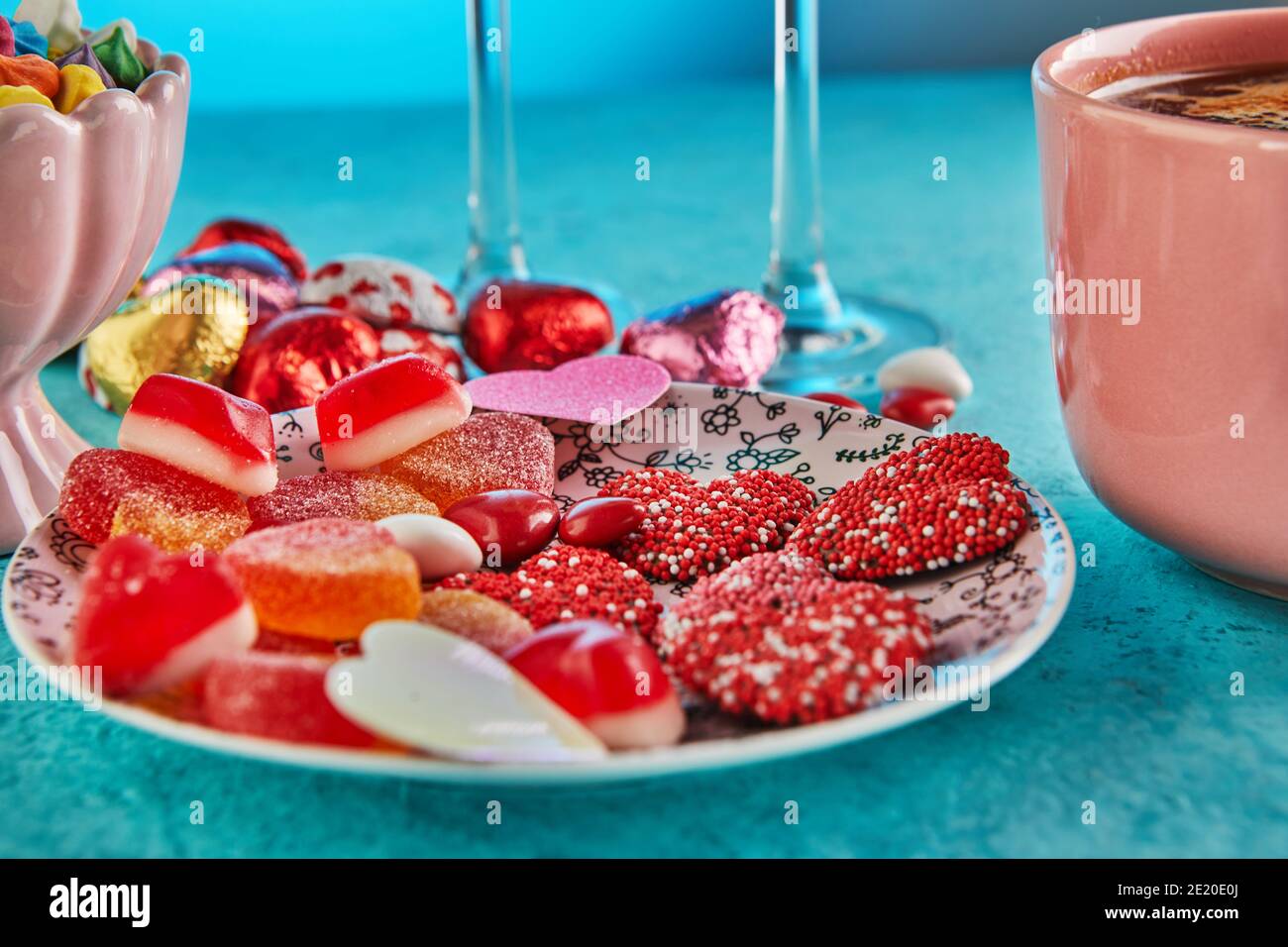 Saint-Valentin ou dîner romantique avec coeurs de bonbons, une tasse de café chaud et élégant cadre de table sur un fond bleu clair Banque D'Images