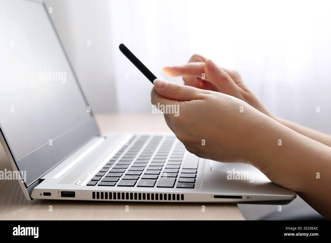 Femme utilisant un smartphone sur l'arrière-plan du clavier de l'ordinateur portable. Concept de communication, de travail et de paiement en ligne Banque D'Images