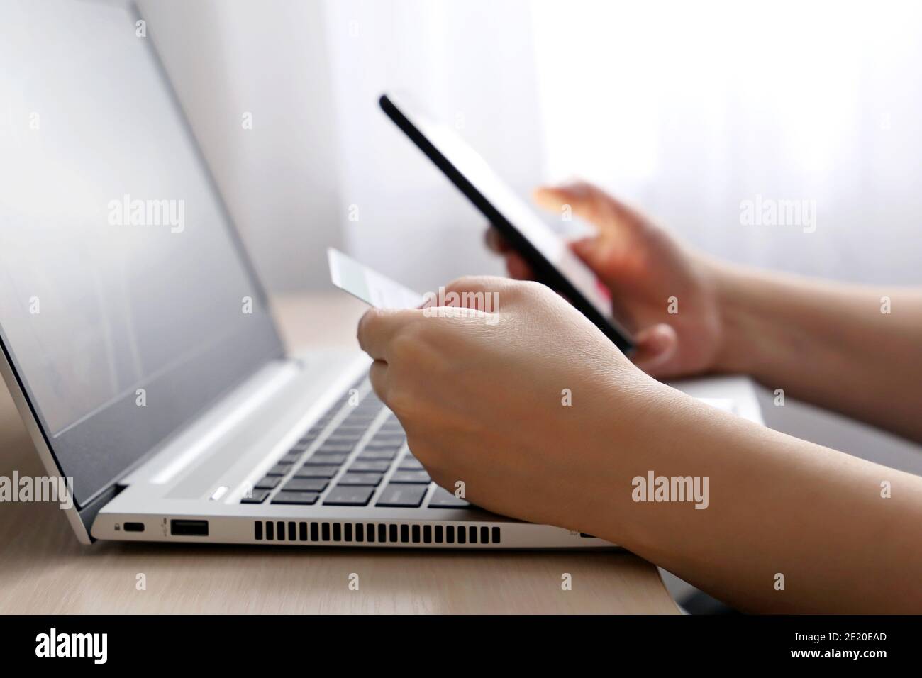 Femme tenant des types de carte de crédit et de smartphone sur le clavier d'ordinateur portable. Concept d'achat et de paiement en ligne Banque D'Images