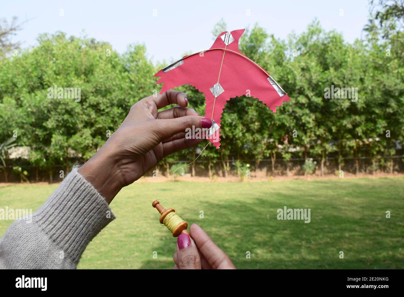 Femme, femme, fille volant d'un jouet miniature cerf-volant avec miniature mignon jouet spool manjha dans le parc. Sur le festival de cerf-volant festival d'uttarayan, makars Banque D'Images