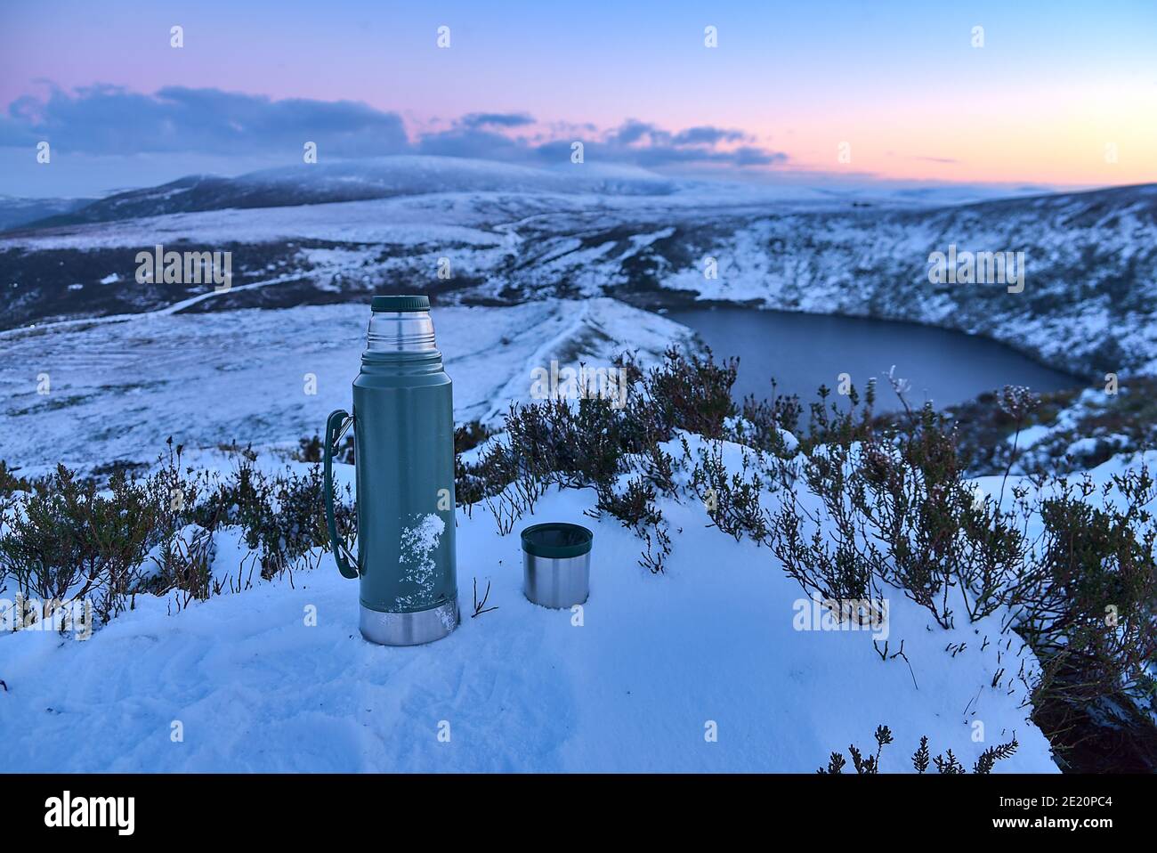 Thermos et une tasse de thé au sommet enneigé et vue panoramique en soirée sur le lac Lough Bray Upper vue depuis Eagles Crag, Ballylerane, Co. Wicklow, Irela Banque D'Images