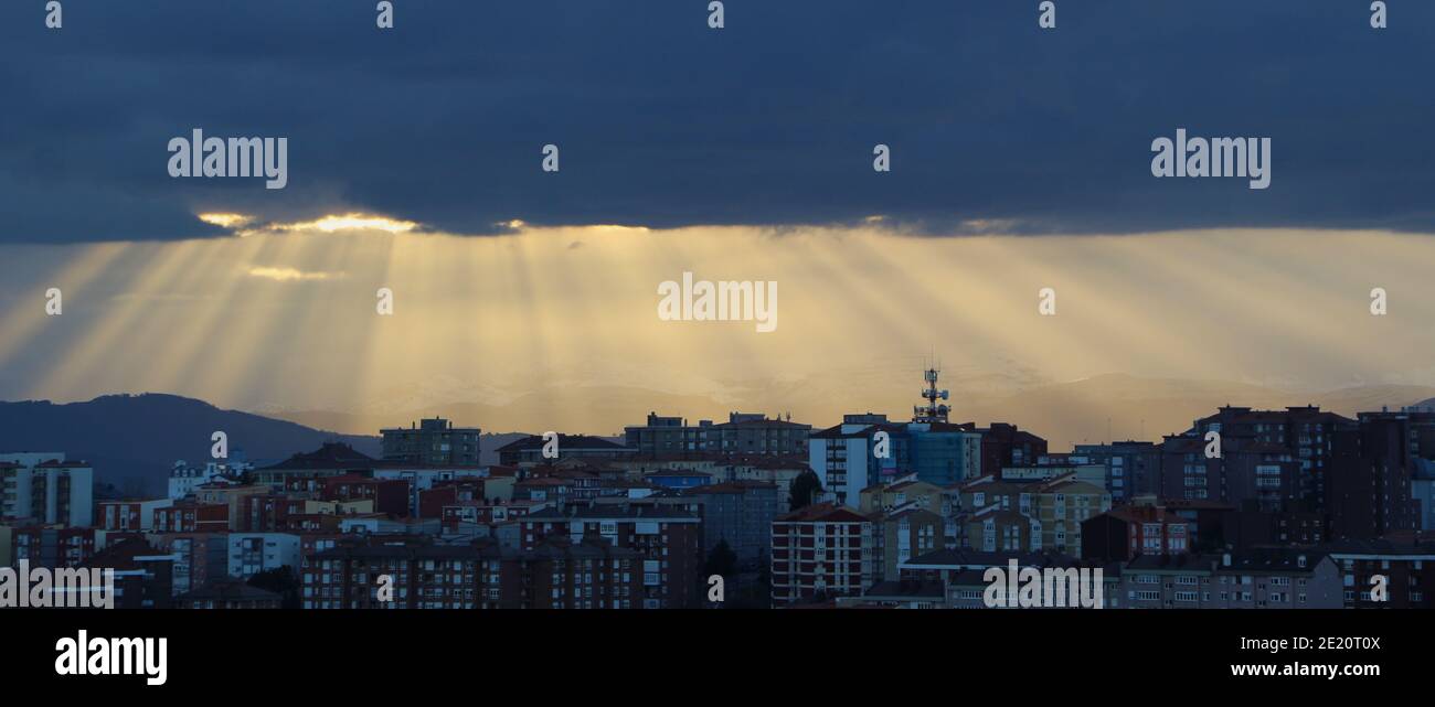 Matin, de lourds nuages sombres avec des poutres de soleil orange s'est enjambé devant les sommets de la montagne à côté de la baie de Santander Cantabria Espagne Banque D'Images