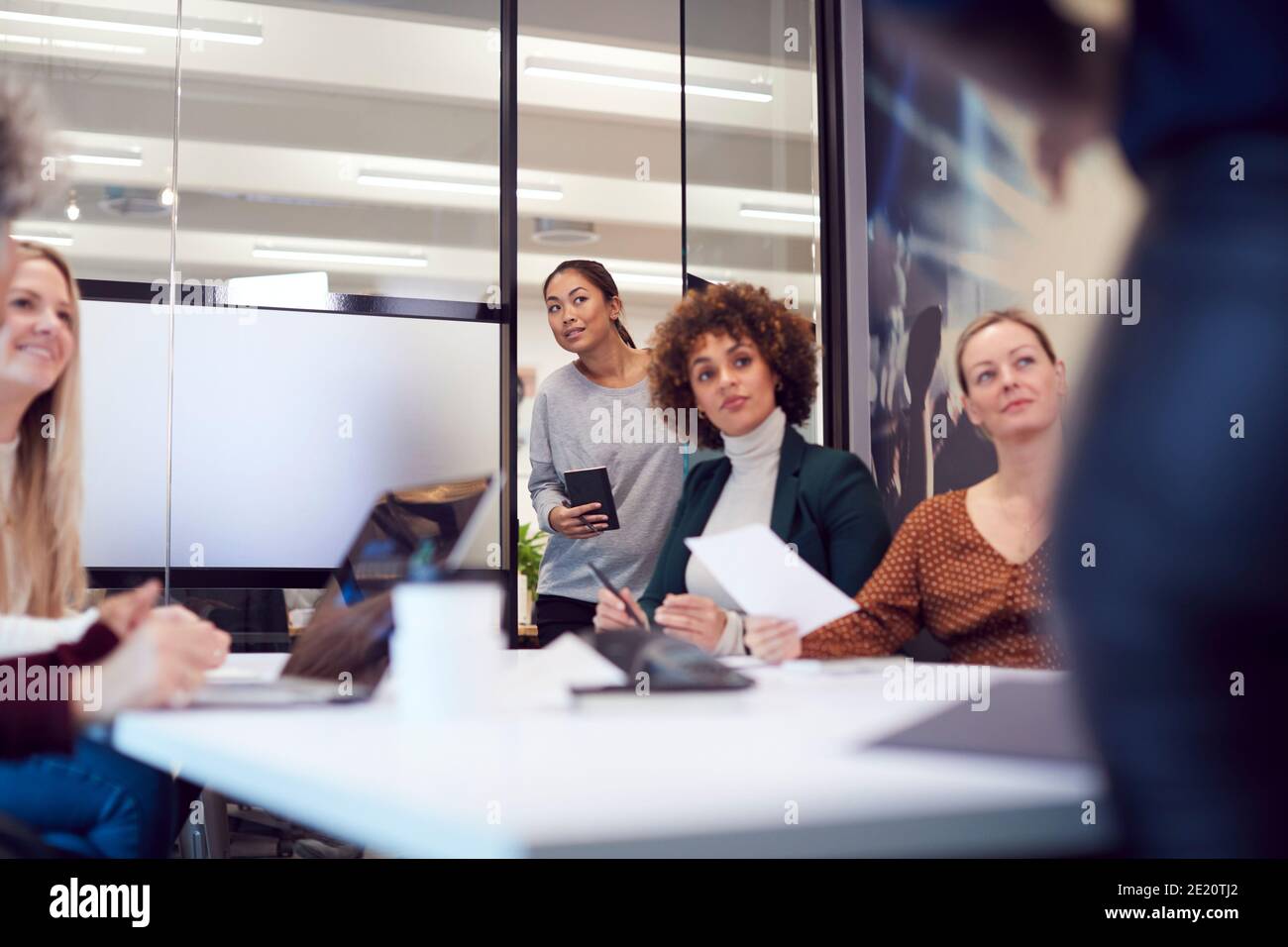Femme d'affaires arrivant en retard pour une présentation par un collègue dans le bureau moderne Banque D'Images
