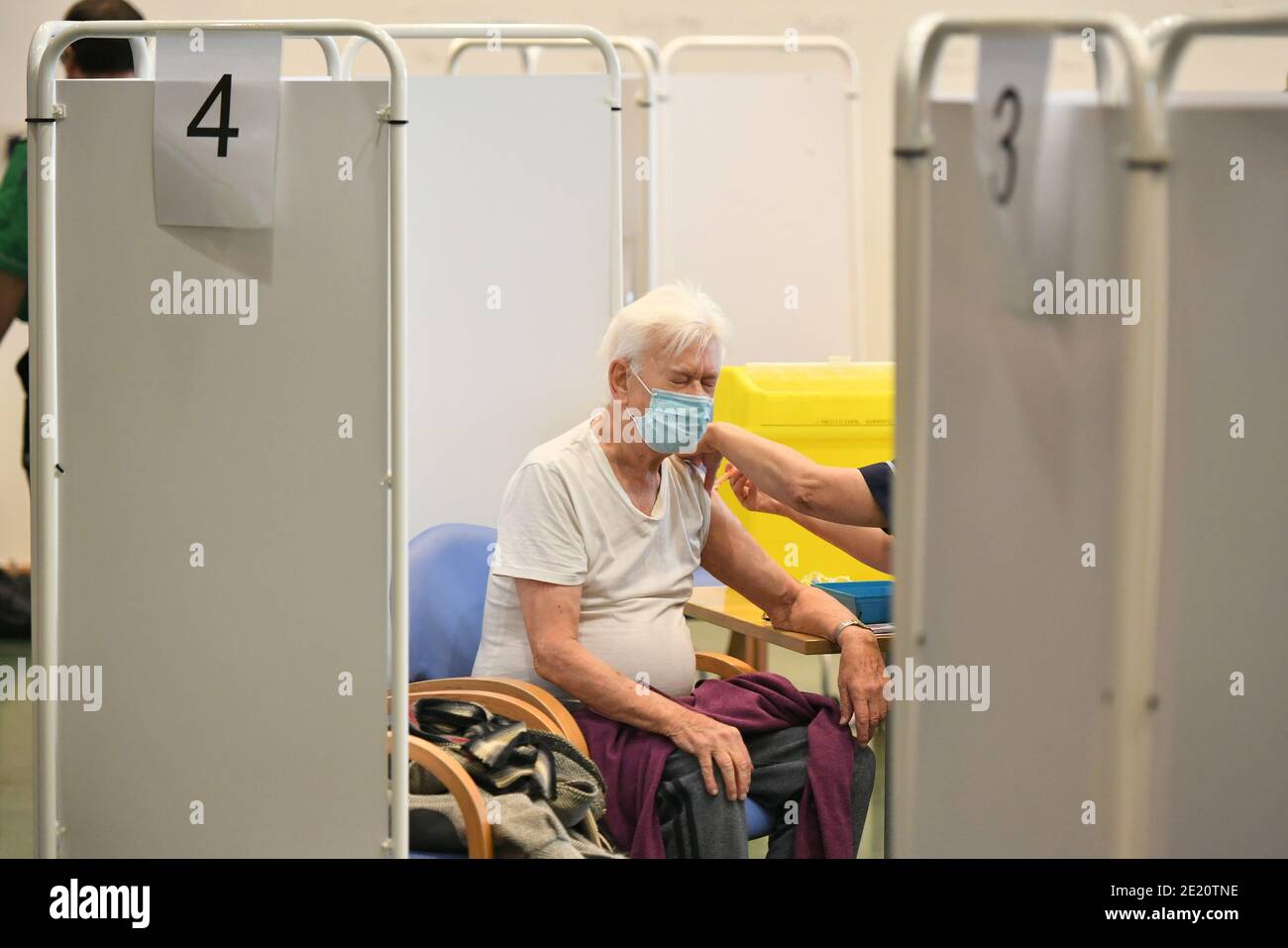 Un homme reçoit une injection du vaccin Oxford/AstraZeneca au centre de vaccination de masse NHS qui a été mis en place dans le champ de course d'Epsom à Surrey et qui est l'une des sept ouvertures aujourd'hui alors que le gouvernement britannique continue d'accélérer le programme de vaccination contre Covid-19. Banque D'Images