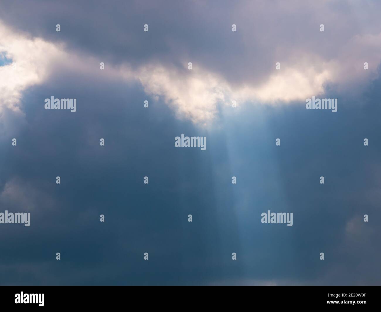 Les rayons du soleil créent un cône de lumière émanant de nuages sombres denses Banque D'Images