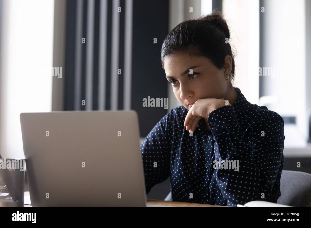 Une jeune femme indienne pensive travaille sur un ordinateur portable Banque D'Images