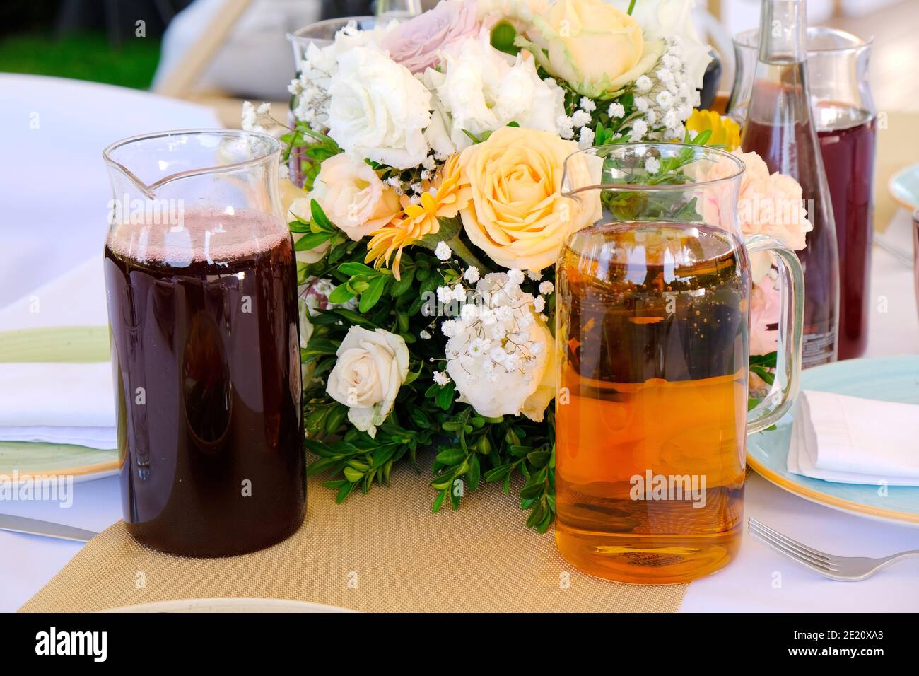 Boissons fraîches, jus de fruits et eau sur une table de banquet décorée de fleurs bouquet dans un restaurant de luxe. Banque D'Images