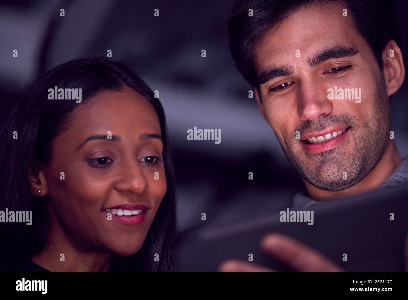 Homme d'affaires et femme d'affaires travaillant tard avec une tablette numérique avec visages Allumé Banque D'Images