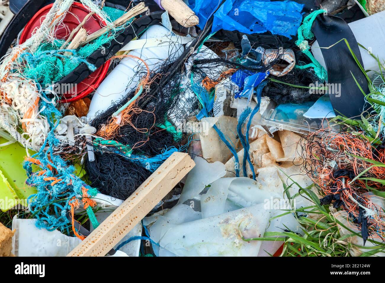 Déchets plastiques avec filets de l'industrie de la pêche enroulés sur une plage côtière causant des déchets de pollution de mer et des dommages environnementaux, stock Banque D'Images